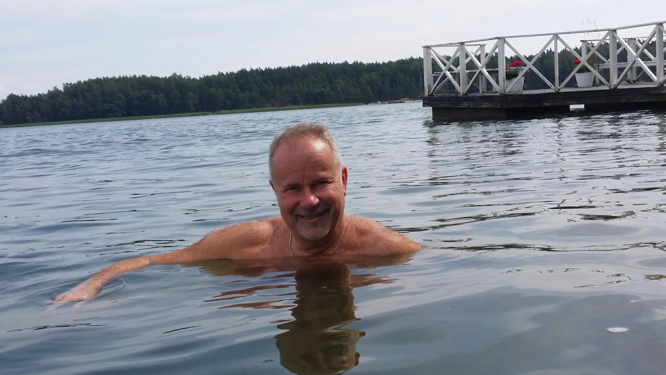 Singer Petri Laaksonen taking a swim, with a pier and the opposite shore in the background