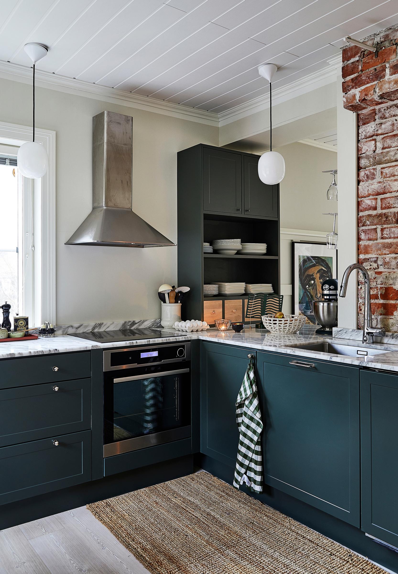 A dark green kitchen with marble countertops from ABL-laatat