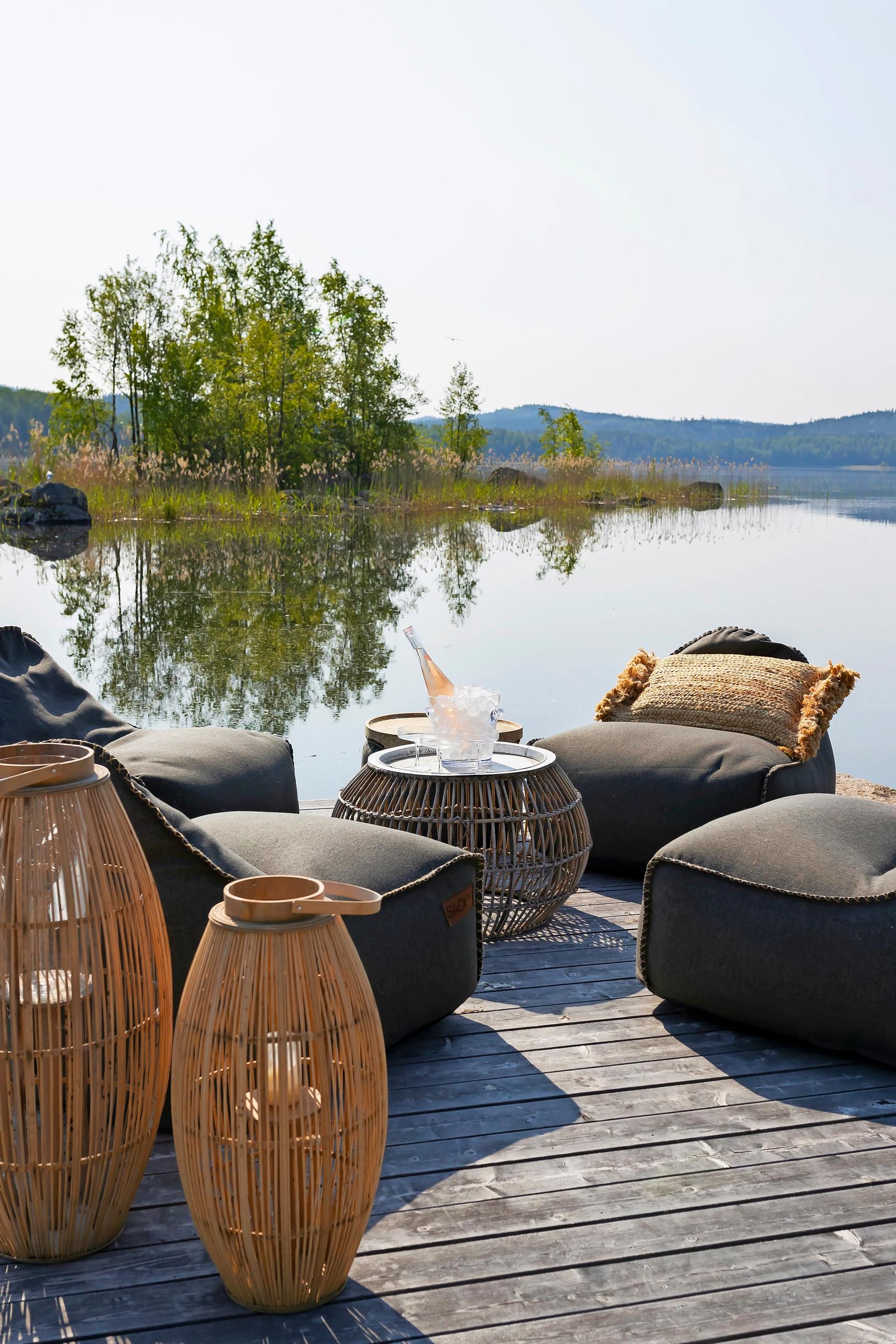 beanbags, a table, and lanterns on the dock, with an island and lake in the background
