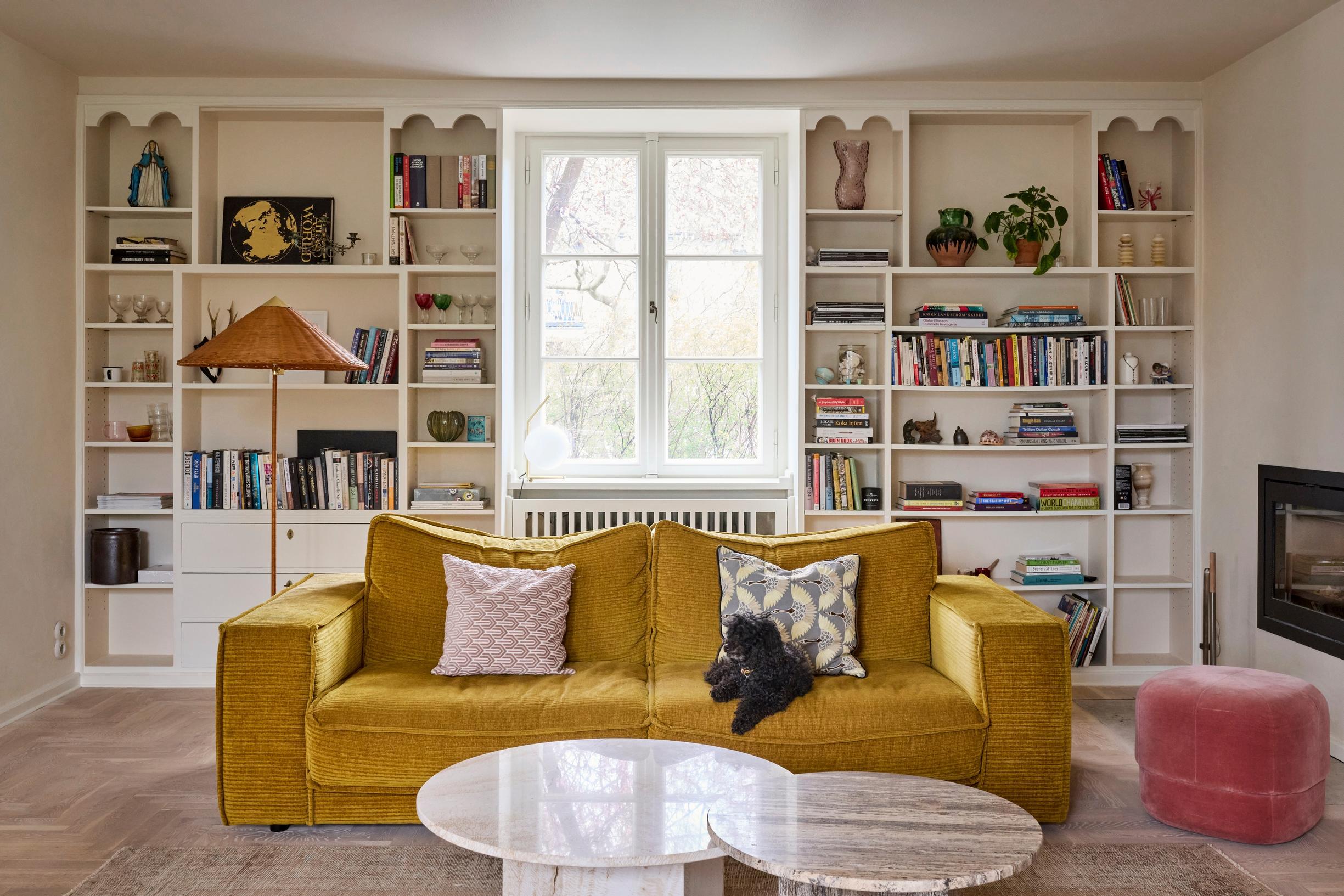 In the living room, the original bookshelf and a large, mustard-colored velvet sofa