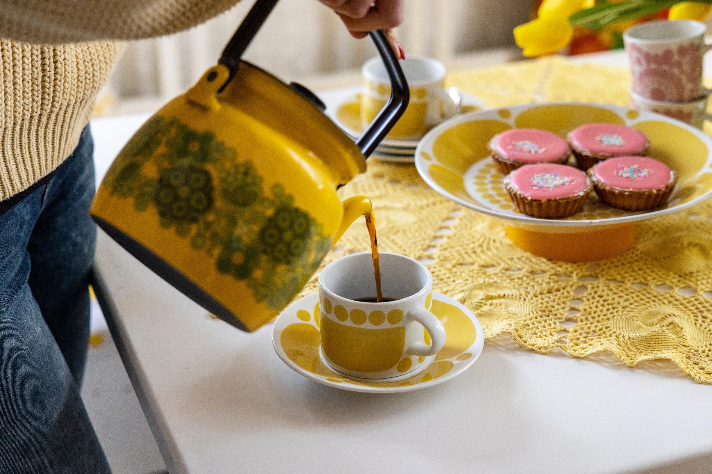 A yellow coffee pot with coffee being poured.
