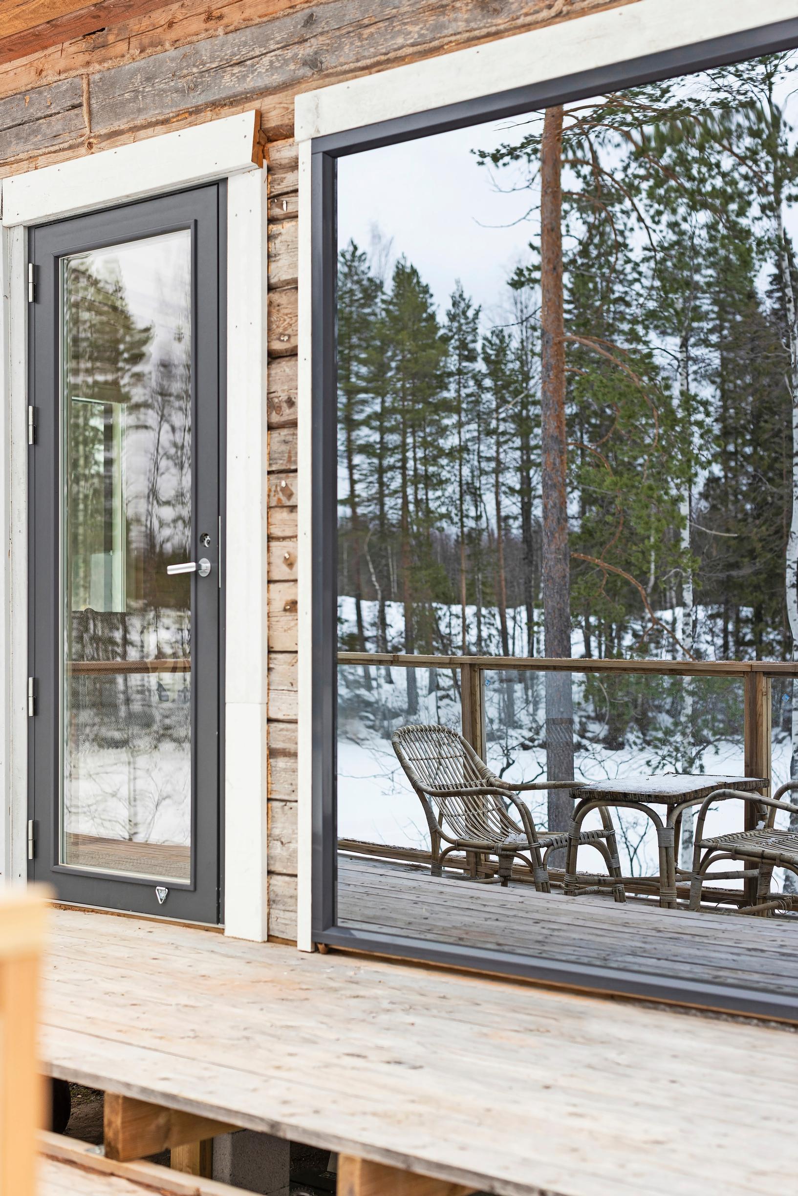 The cabin’s terrace reflected in the windows, featuring a table set.