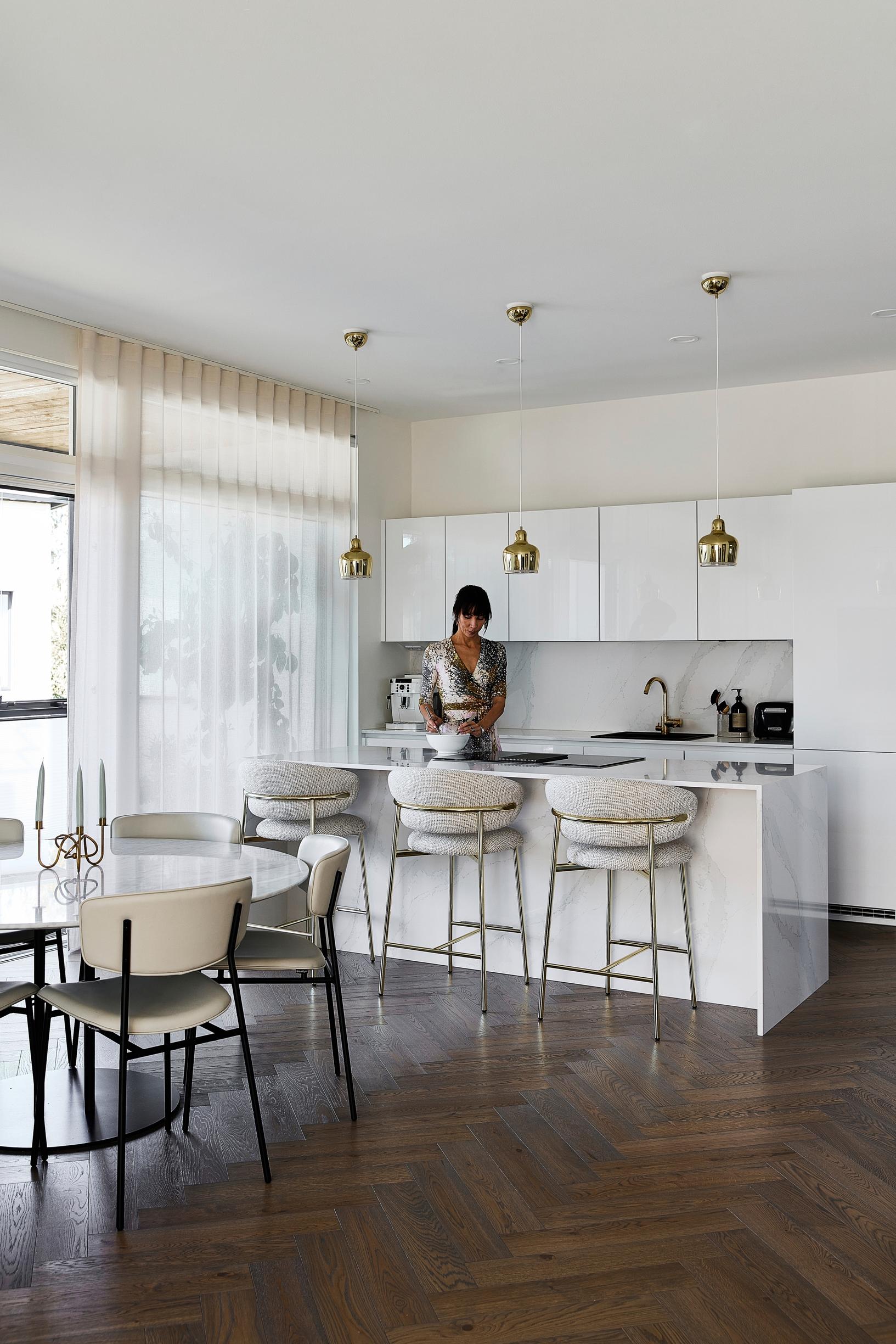 A white open-plan kitchen with an island and bar stools.