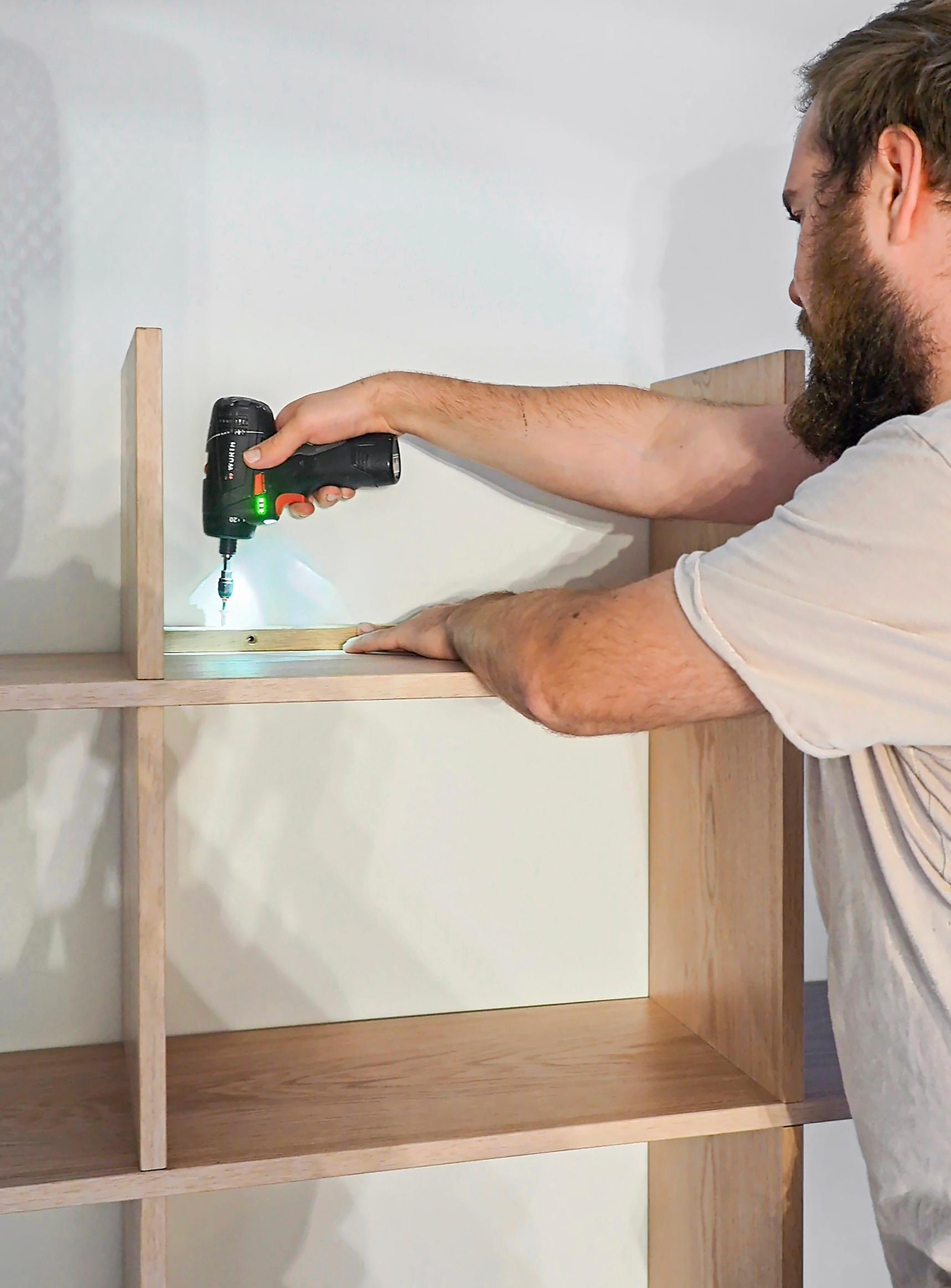 Attaching the wooden shelf to the wall.