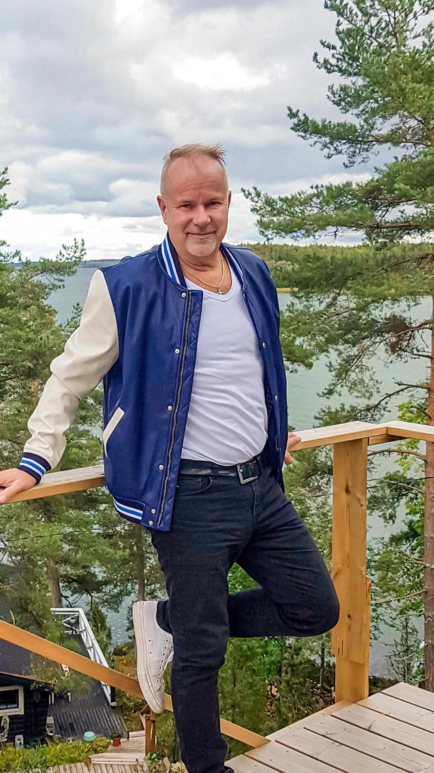 Singer Petri Laaksonen leans on a terrace railing high on a hill, with the sea in the background