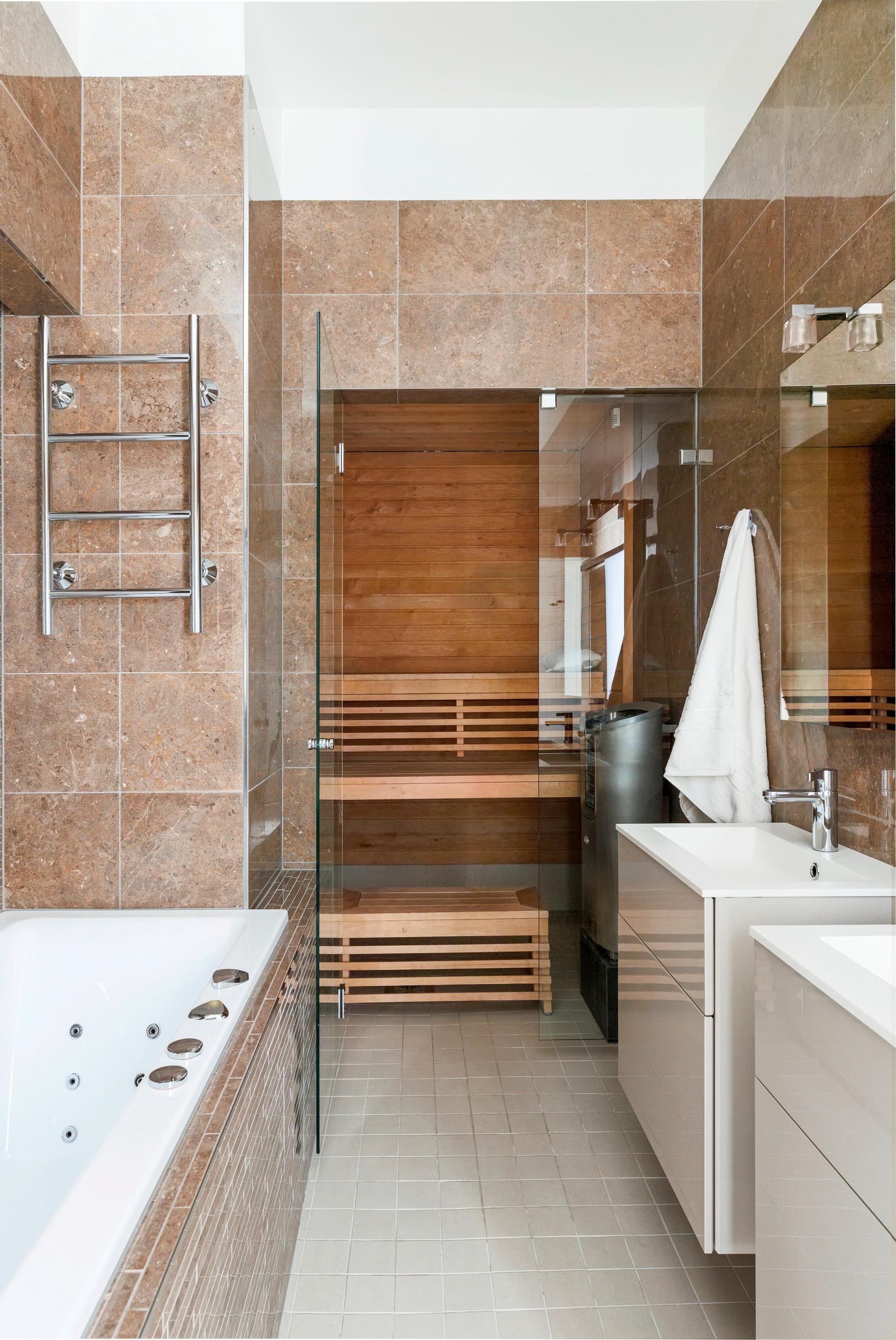 A brown-toned bathroom with a bathtub and sauna.