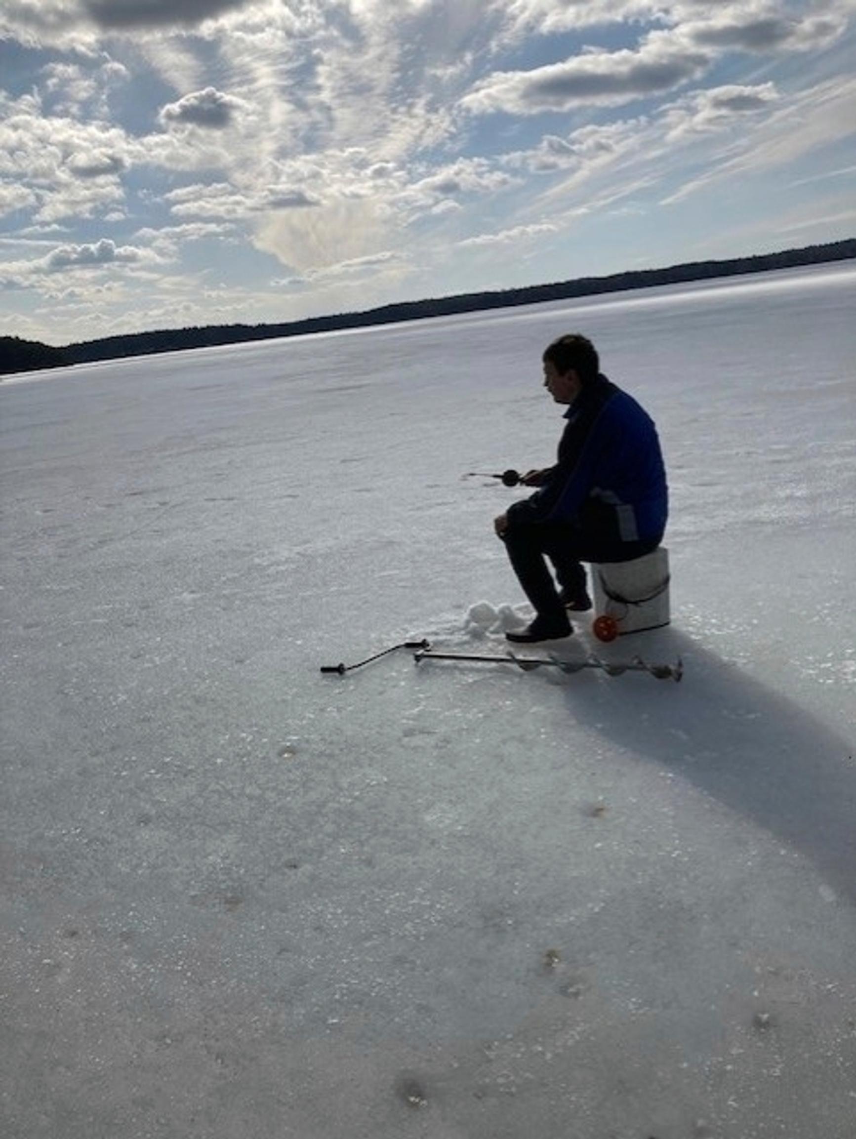 Teuvo Heikkonen sits on the frozen lake, ice fishing