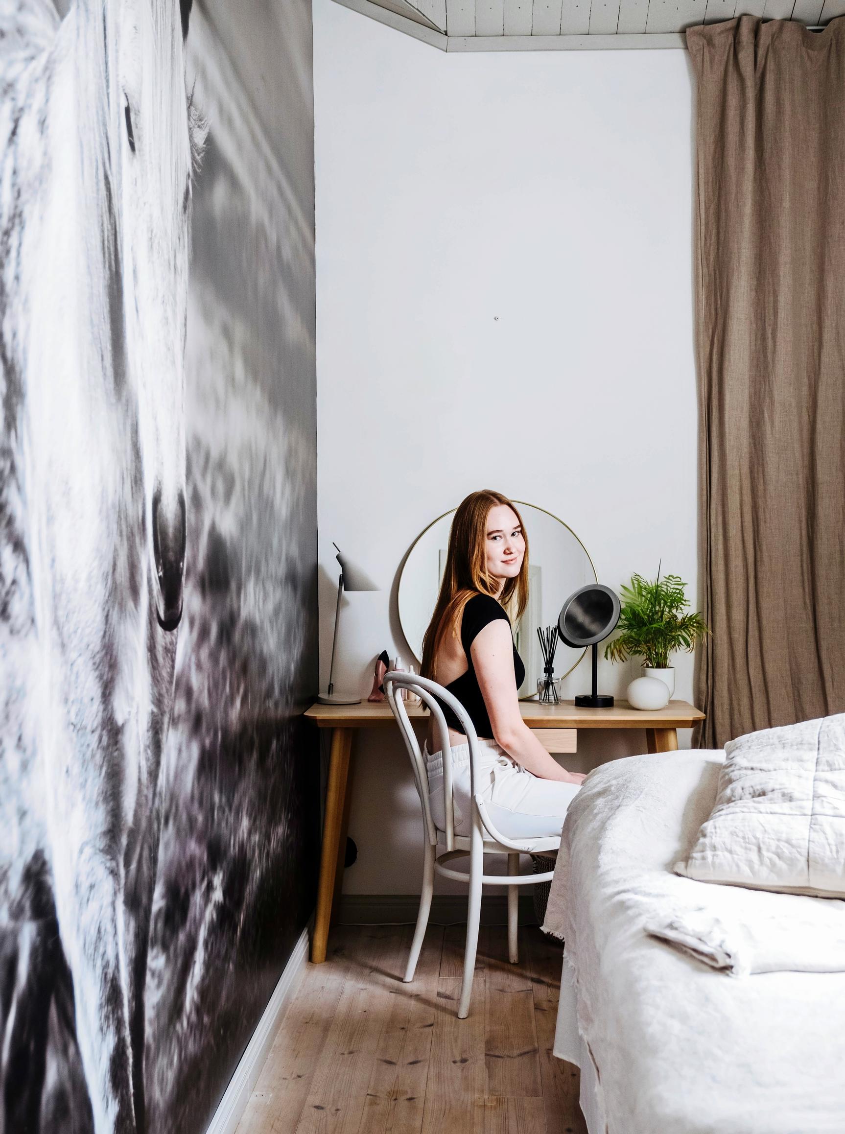 Aivi sitting at a desk in her room.