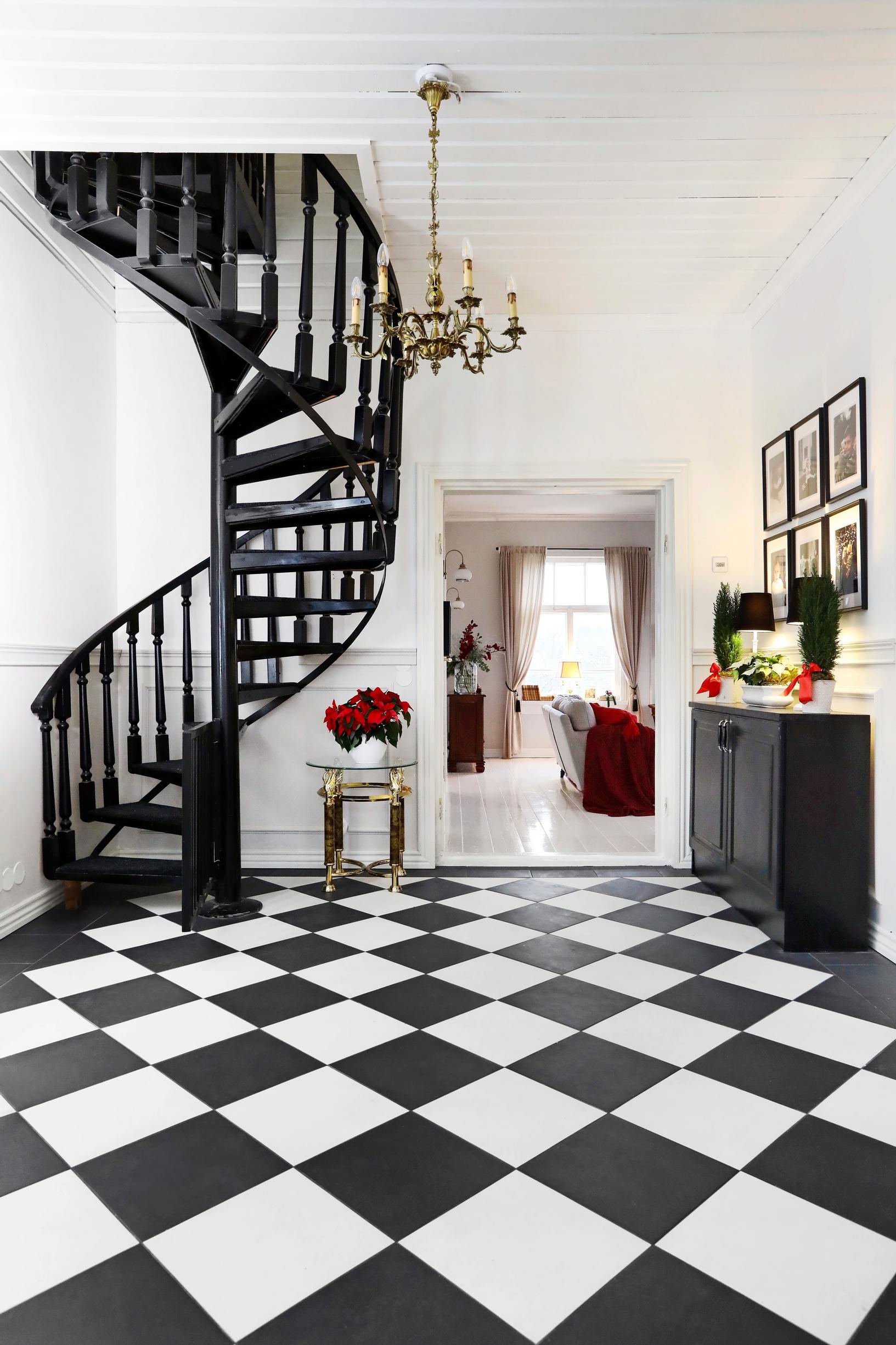Checkerboard-tiled floor in the guest entryway and black spiral stairs