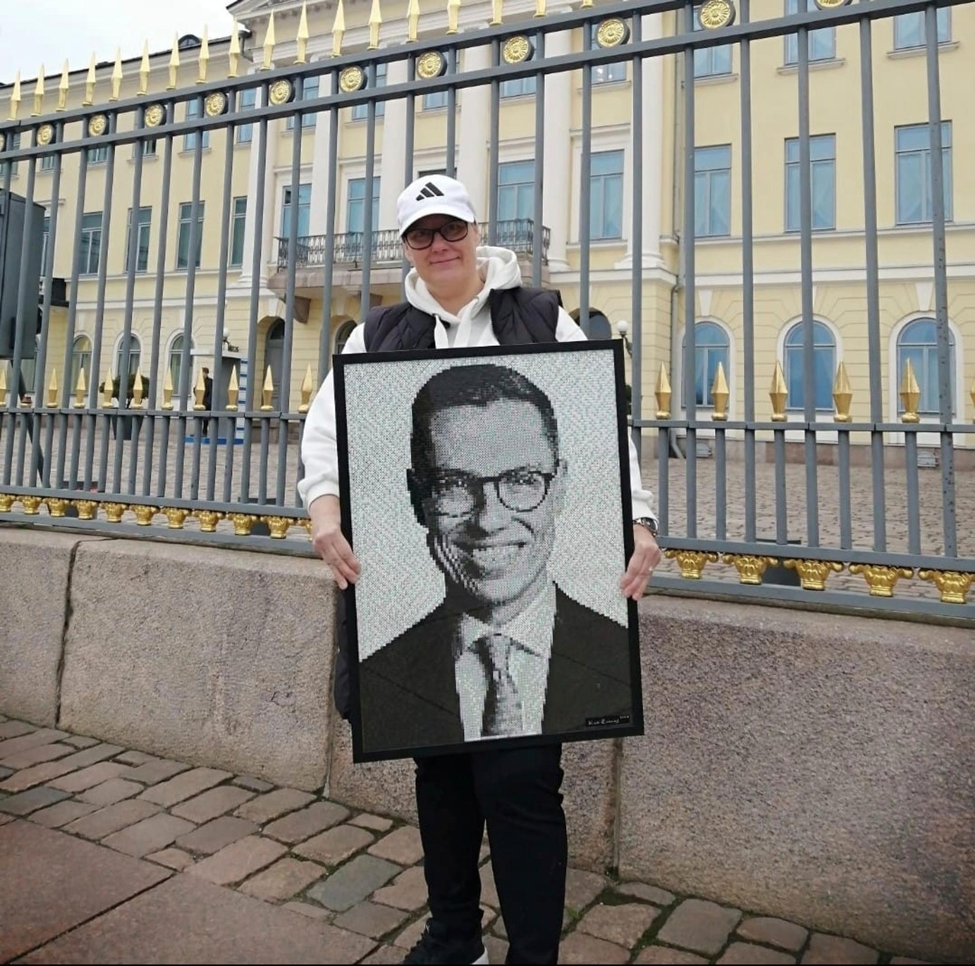 Kati outside the Presidential Palace holding her portrait of Alexander Stubb.