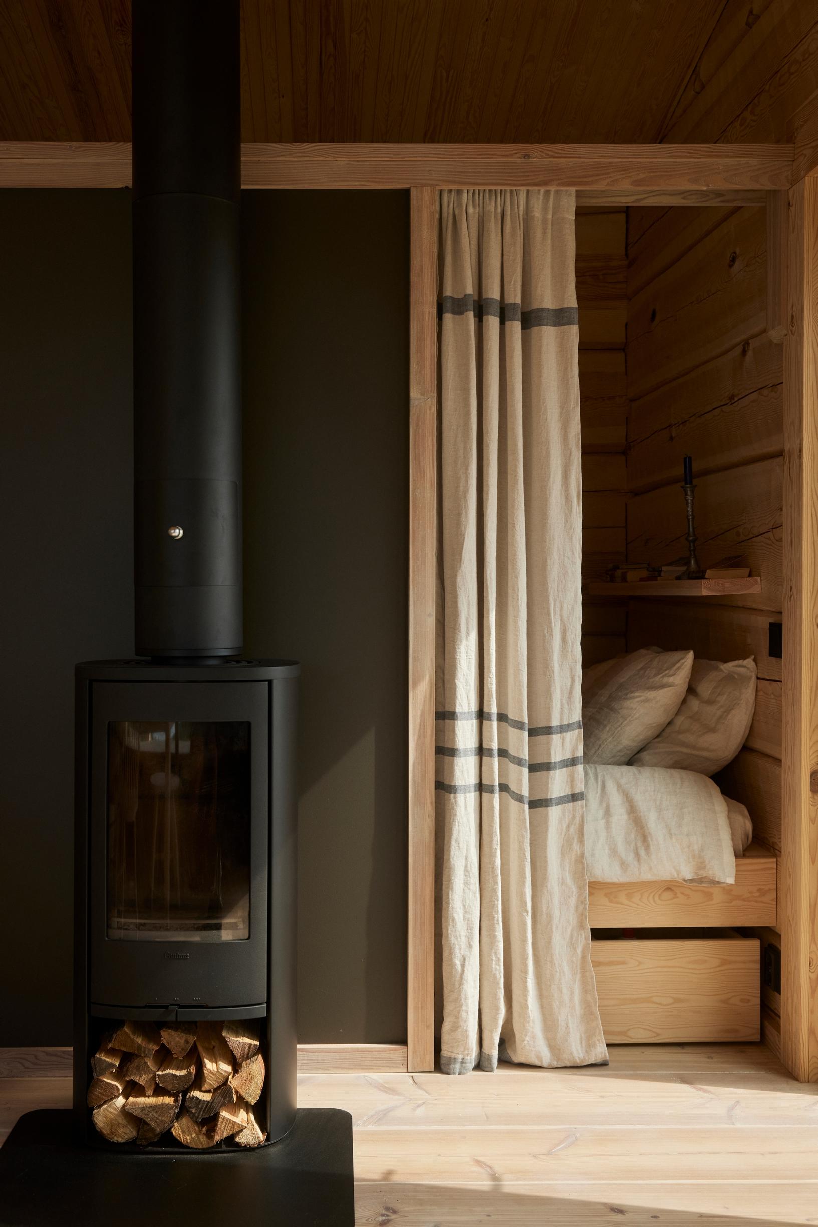 A black fireplace next to the curtained bed.