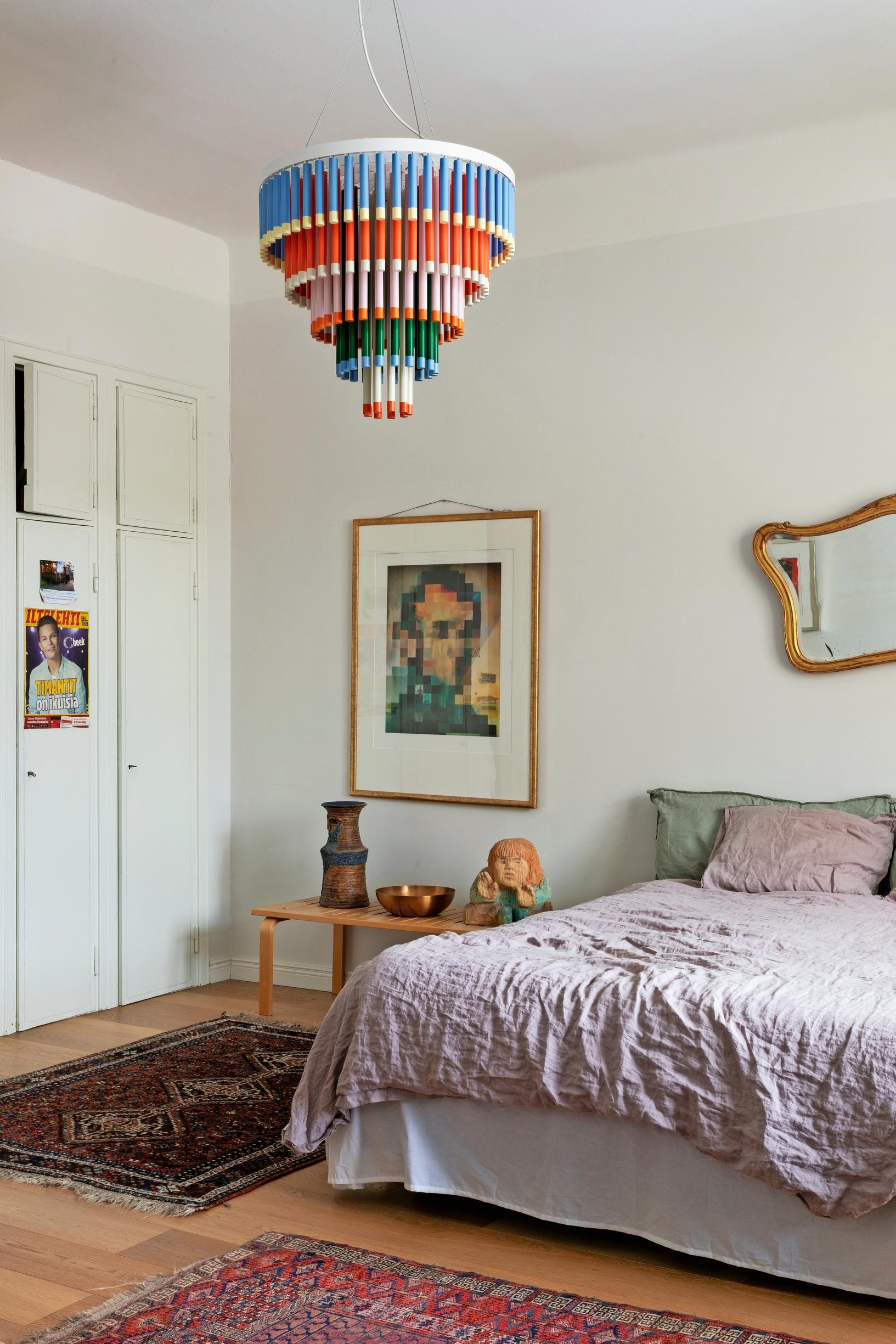 Bedroom with a bed, next to it a bench displaying ceramic pieces.