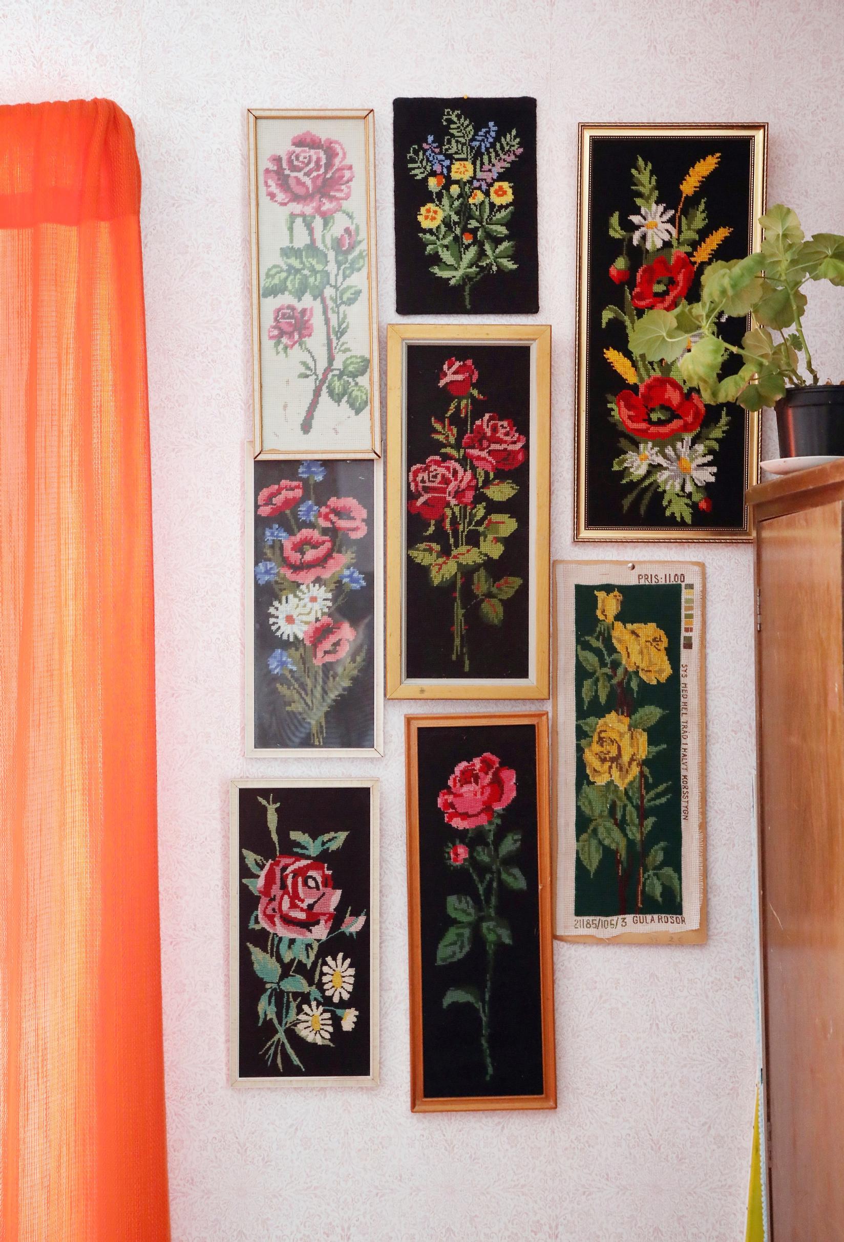 A collection of floral needlepoint pieces on the wall.