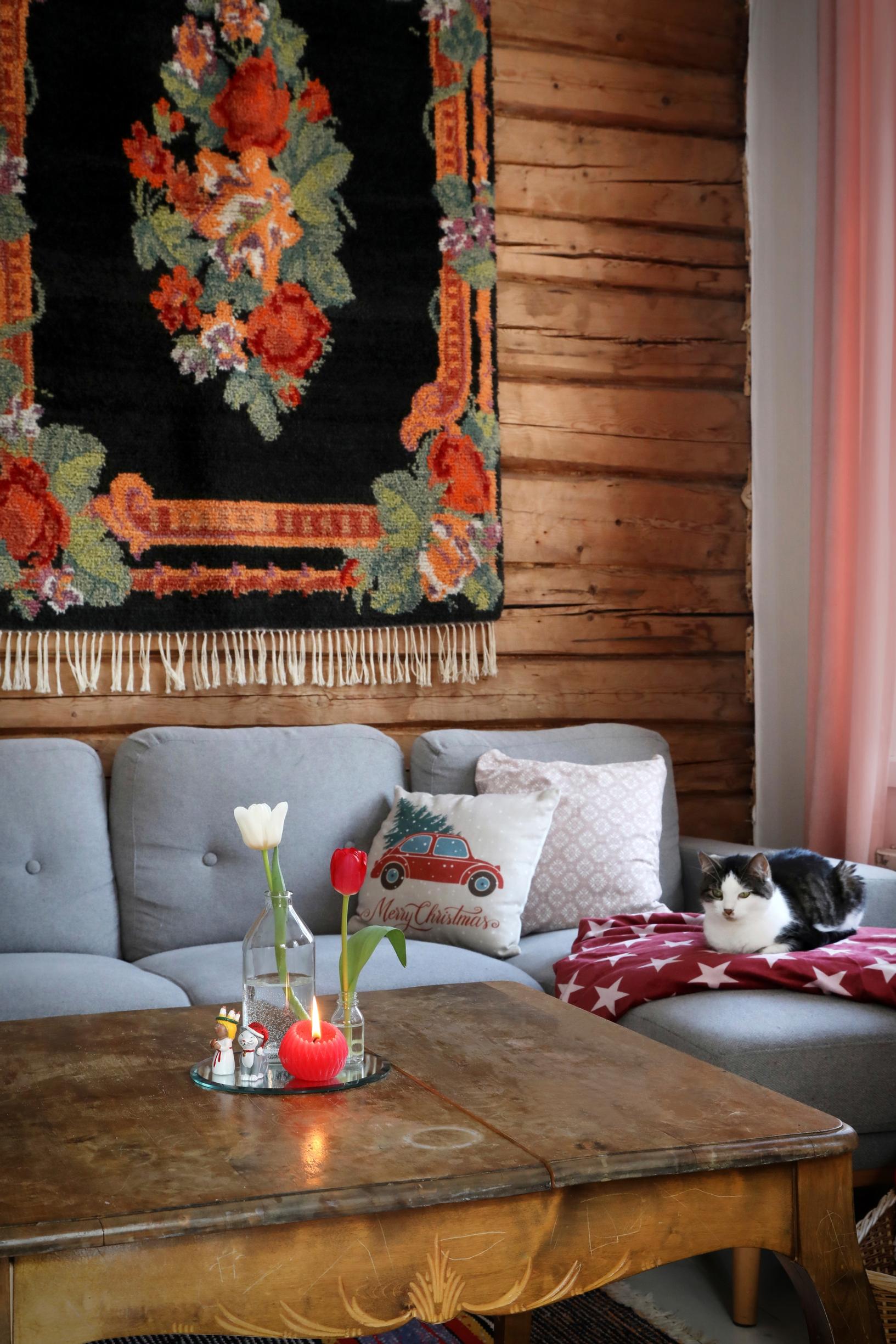 A rose-patterned ryijy rug on the living room’s log wall