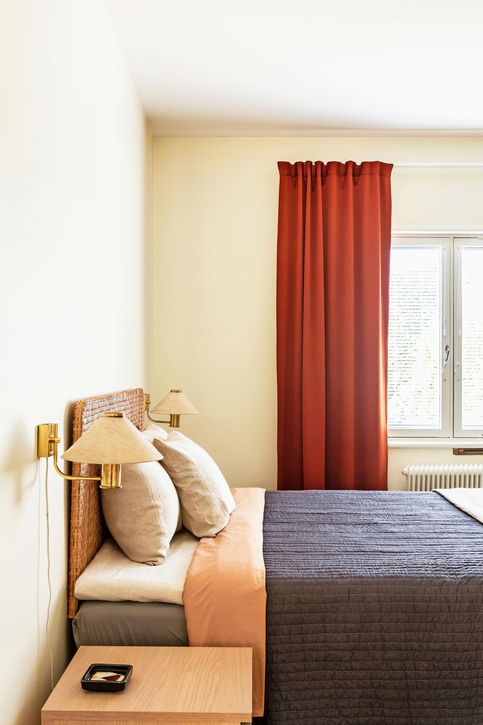 Reddish-brown curtains and a rattan headboard in the bedroom