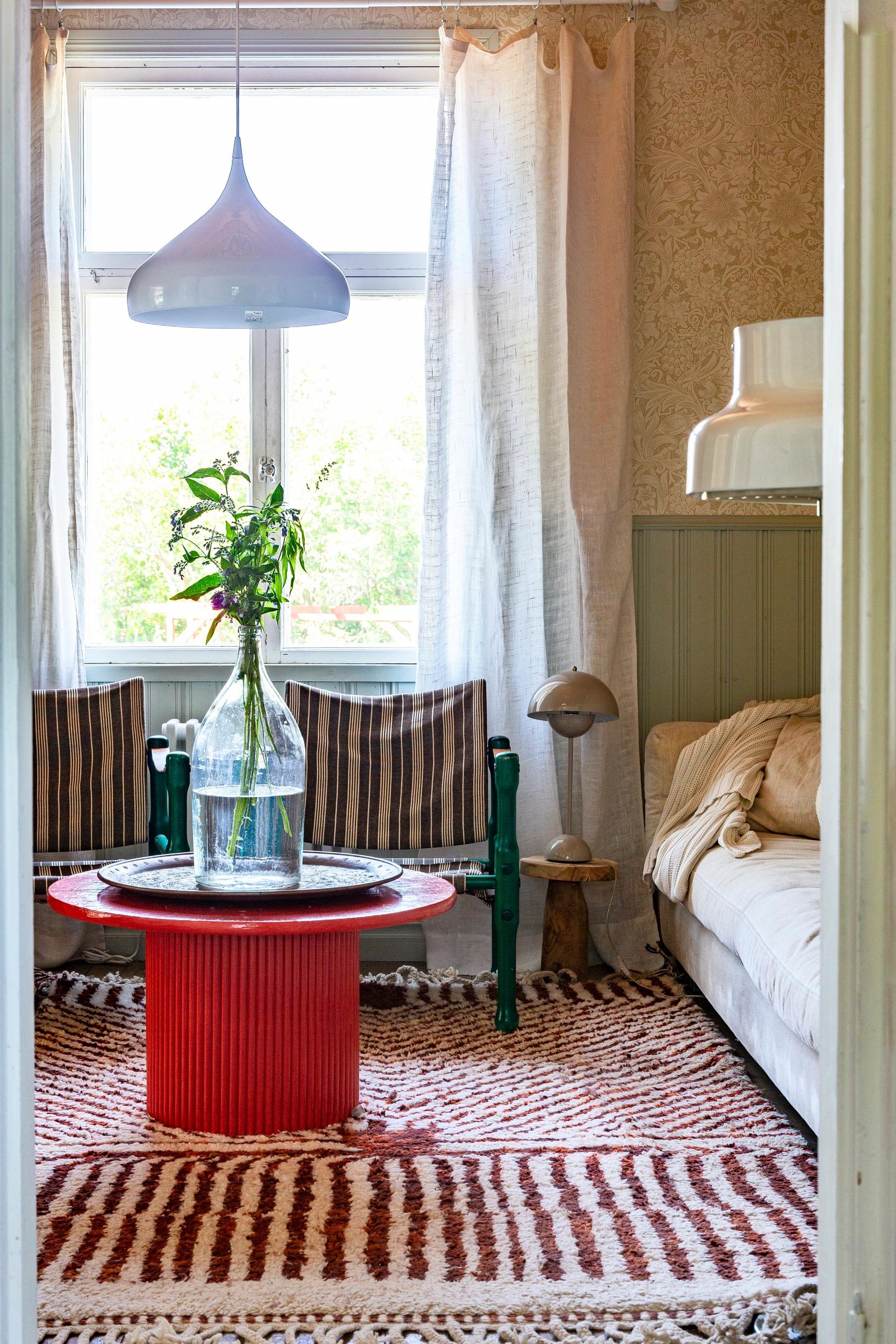 In the TV room, a red table and a striped Moroccan rug.