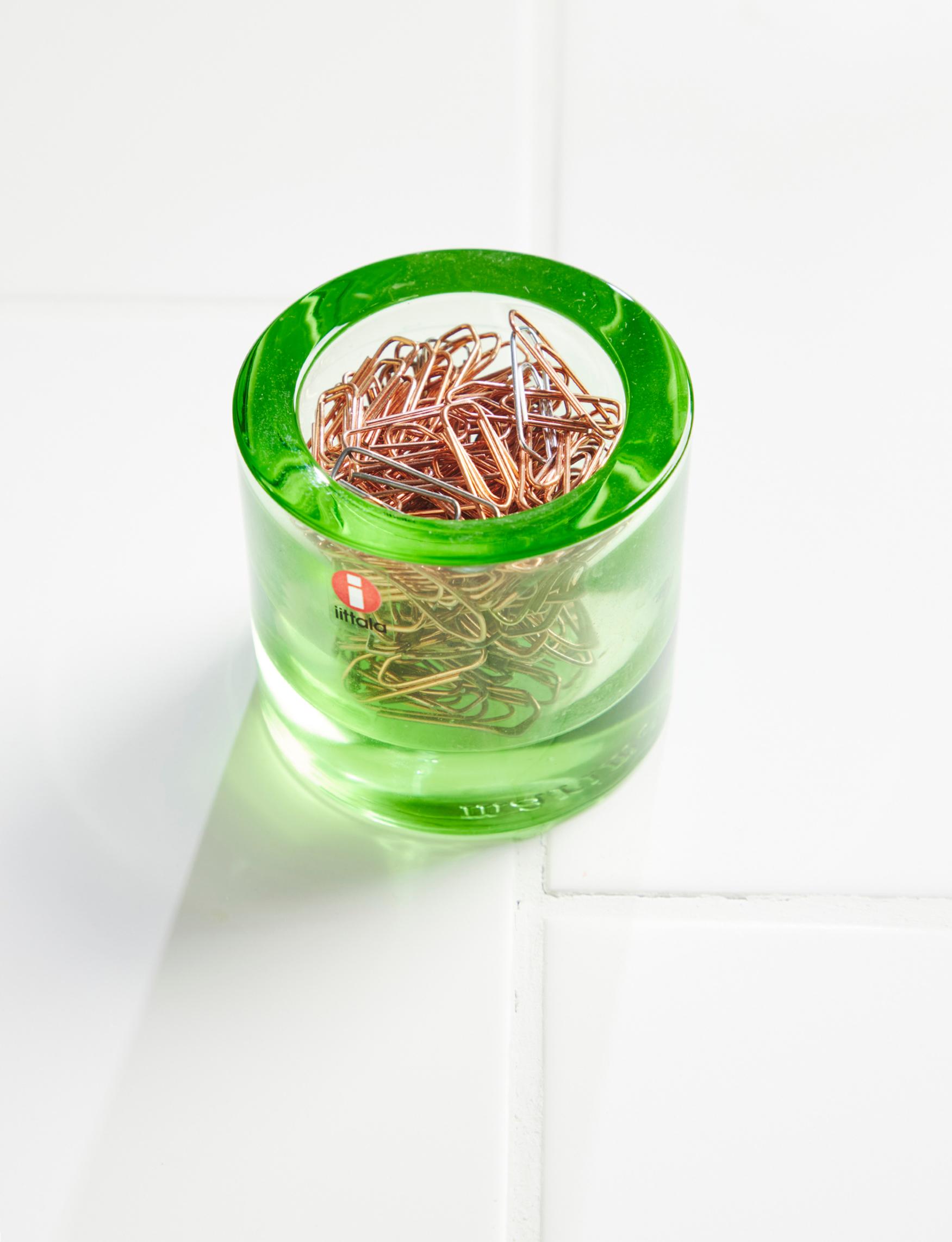 Paper clips in a green Kivi tea light holder.