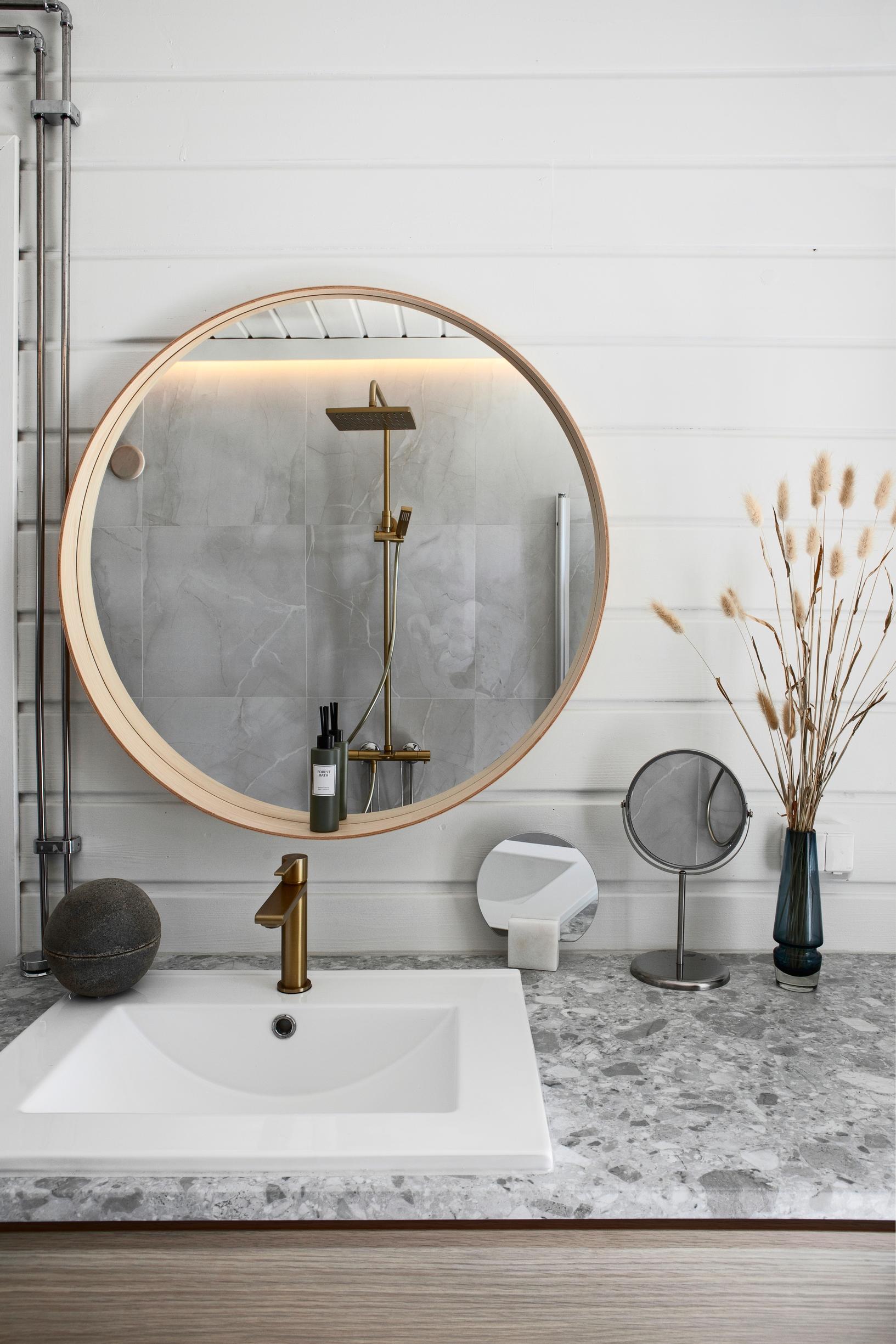 A round mirror and a laminate countertop in the bathroom