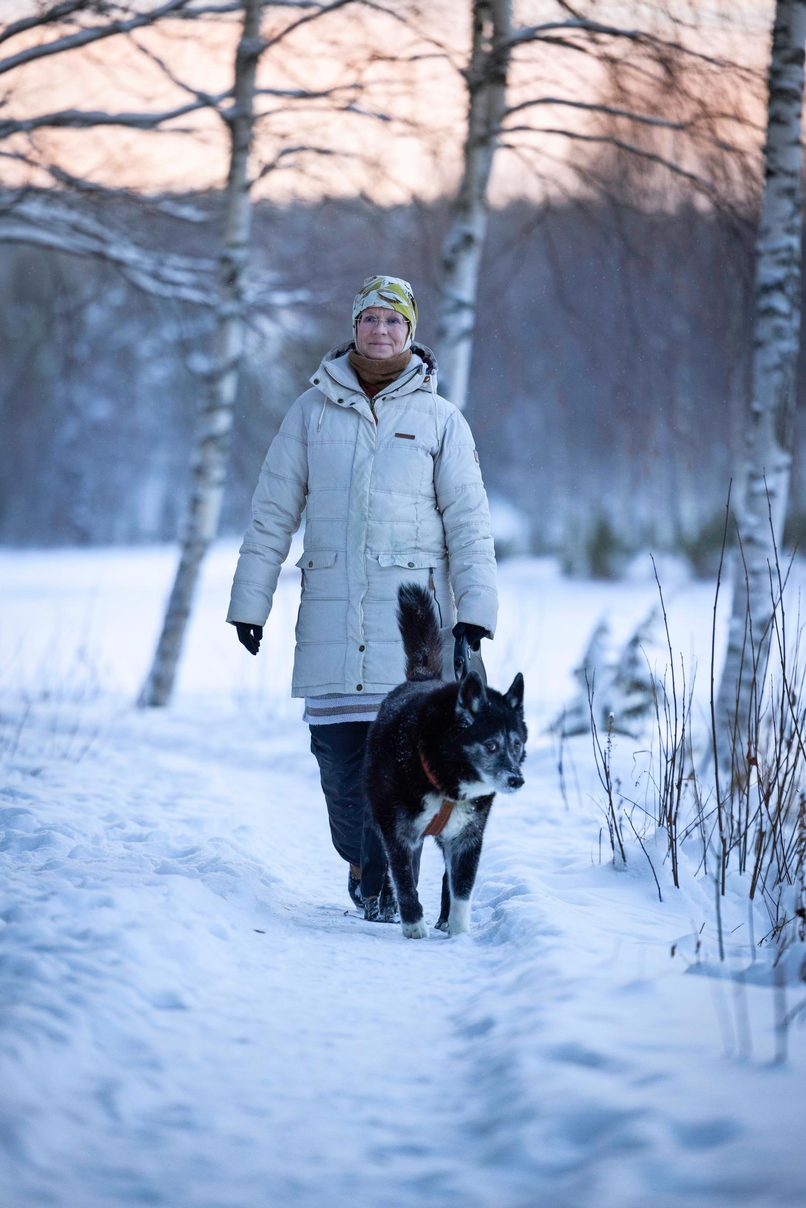 a woman and a dog on a walk in a snowy forest