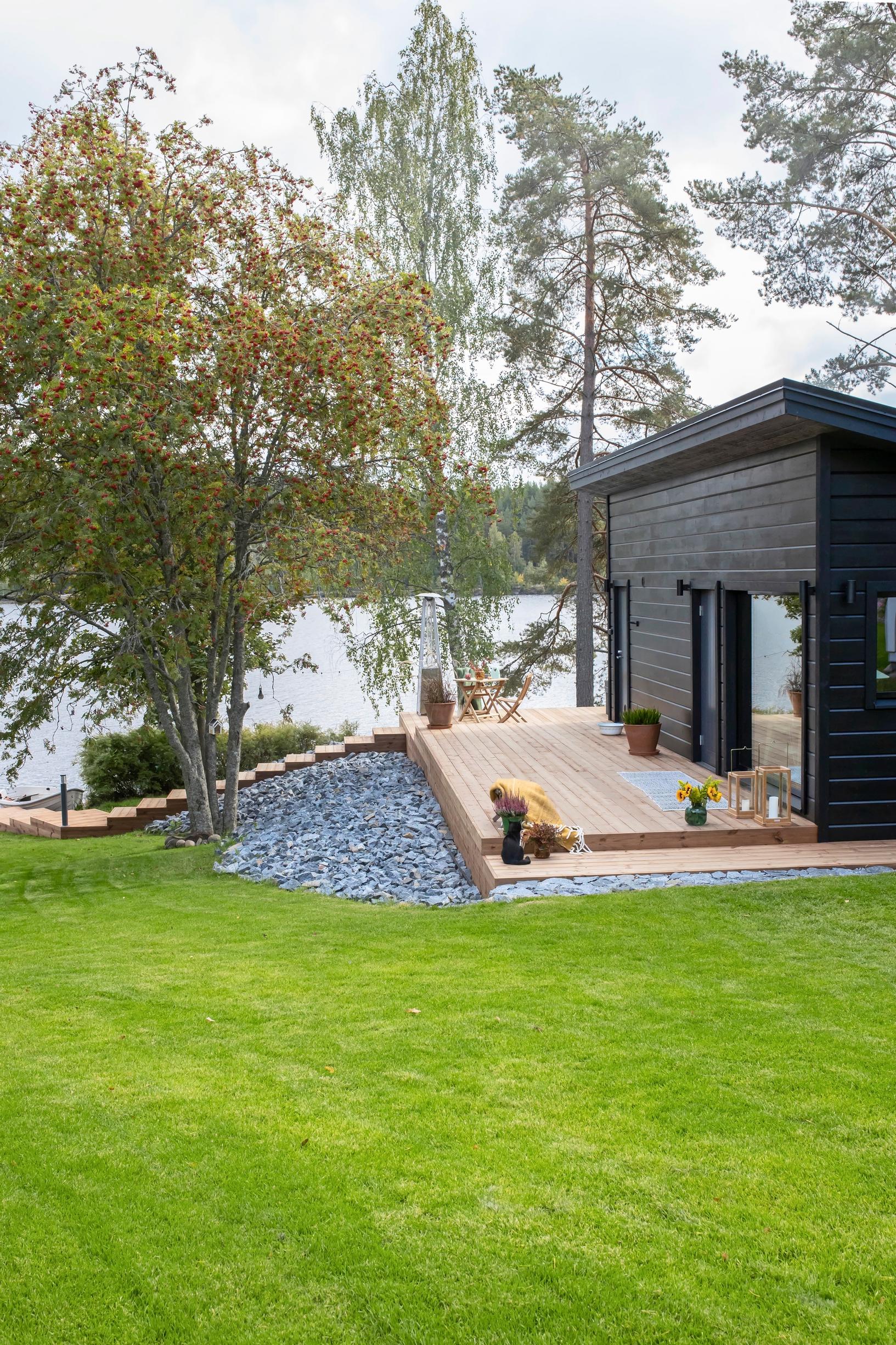 A black sauna cottage with a lawn