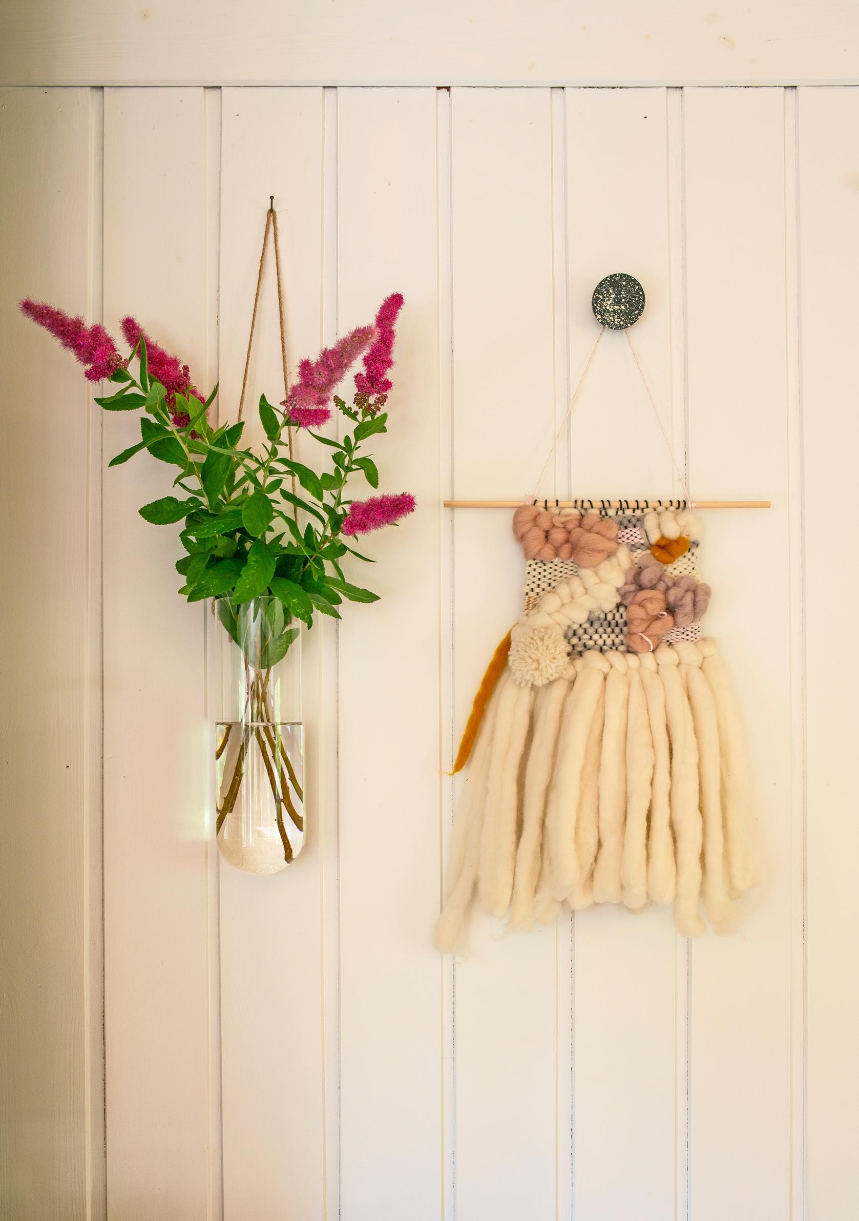 A small wall rug and a red flower hanging on the wall