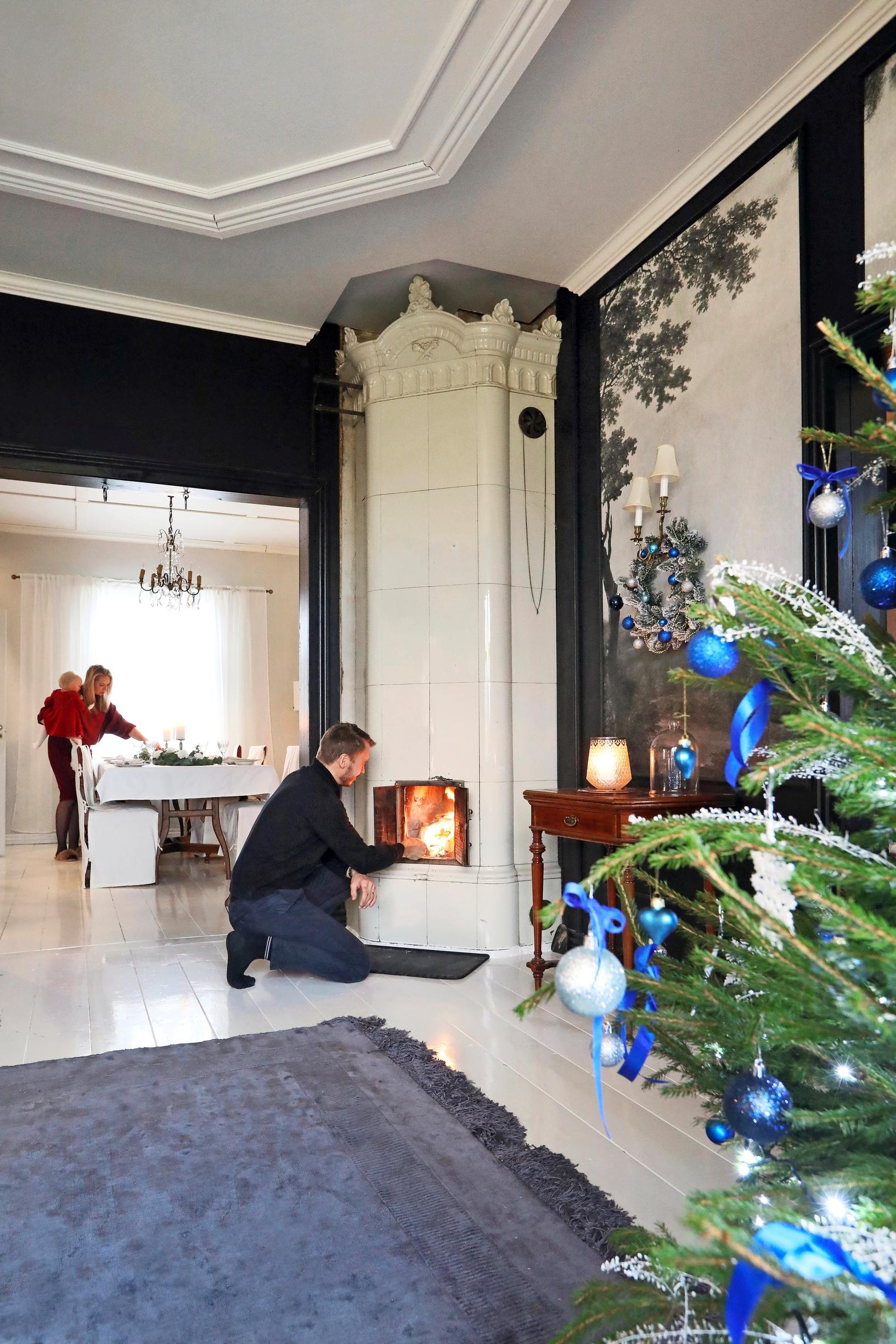 Manu lighting a fire in the old tiled stove in a festively decorated space