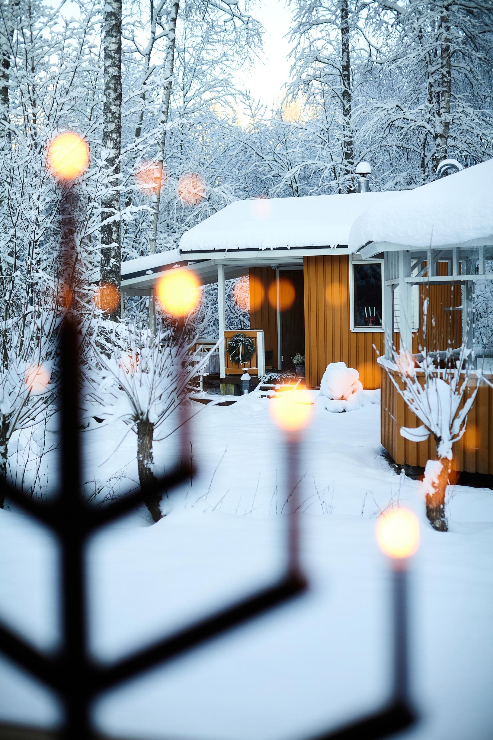 a yellow yard sauna and a grill shelter, with a Christmas candelabra in the window