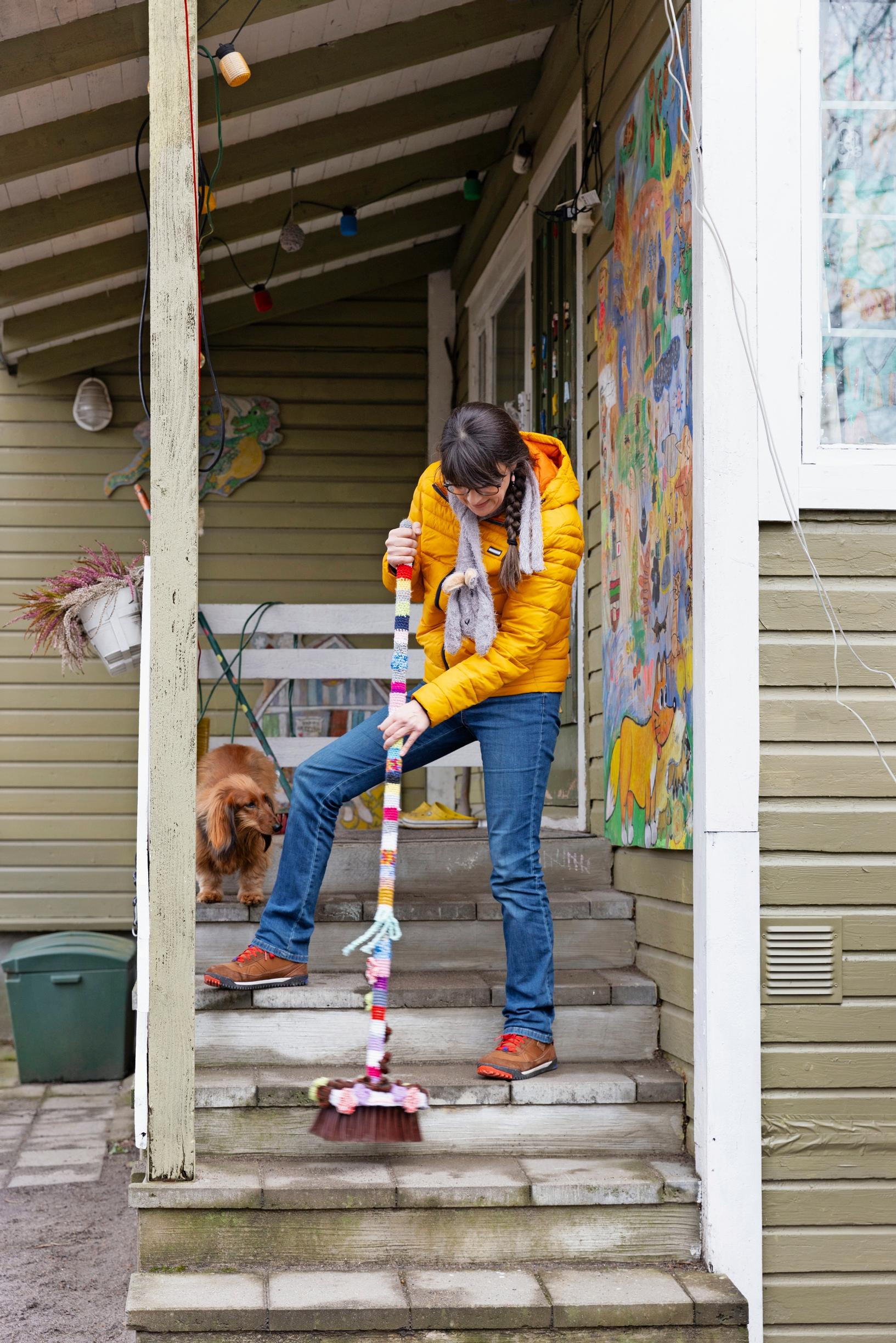 a woman sweeping a porch, with a dog by her side