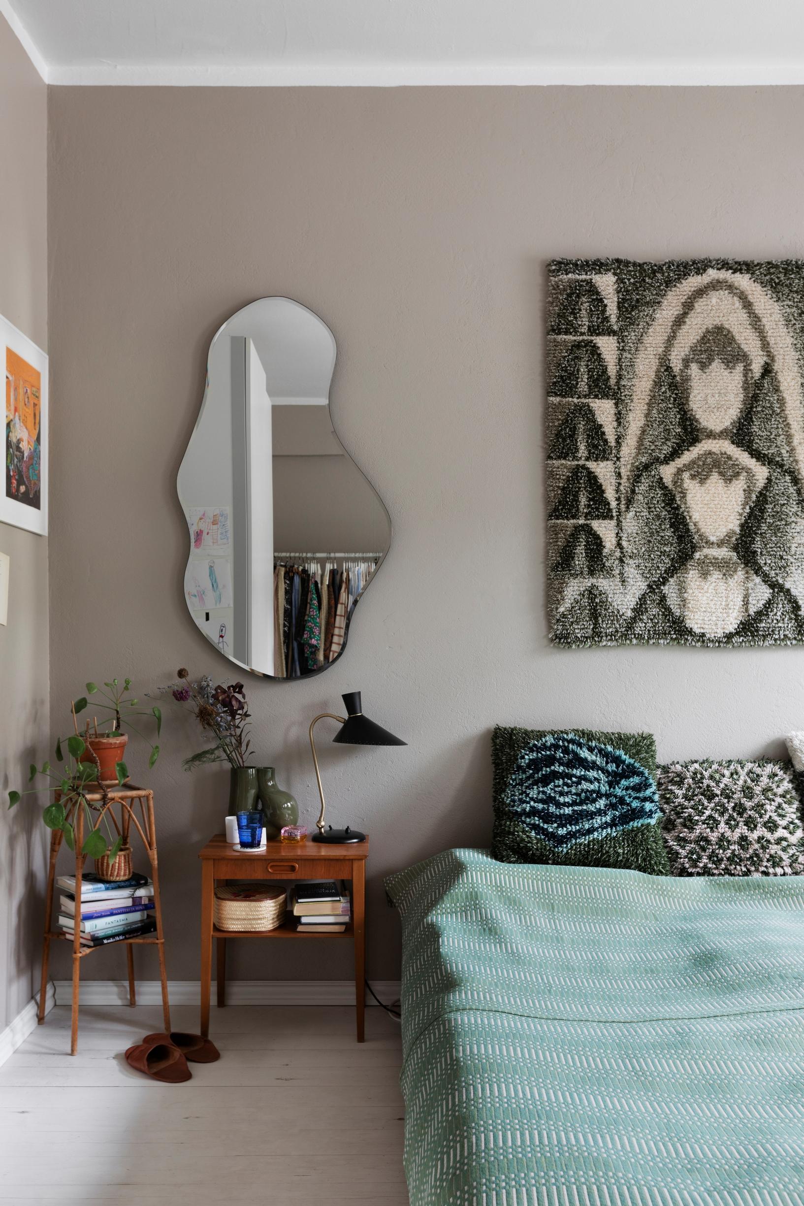 In the bedroom, a mirror and a wall tapestry and ryijy pillows woven by grandmother