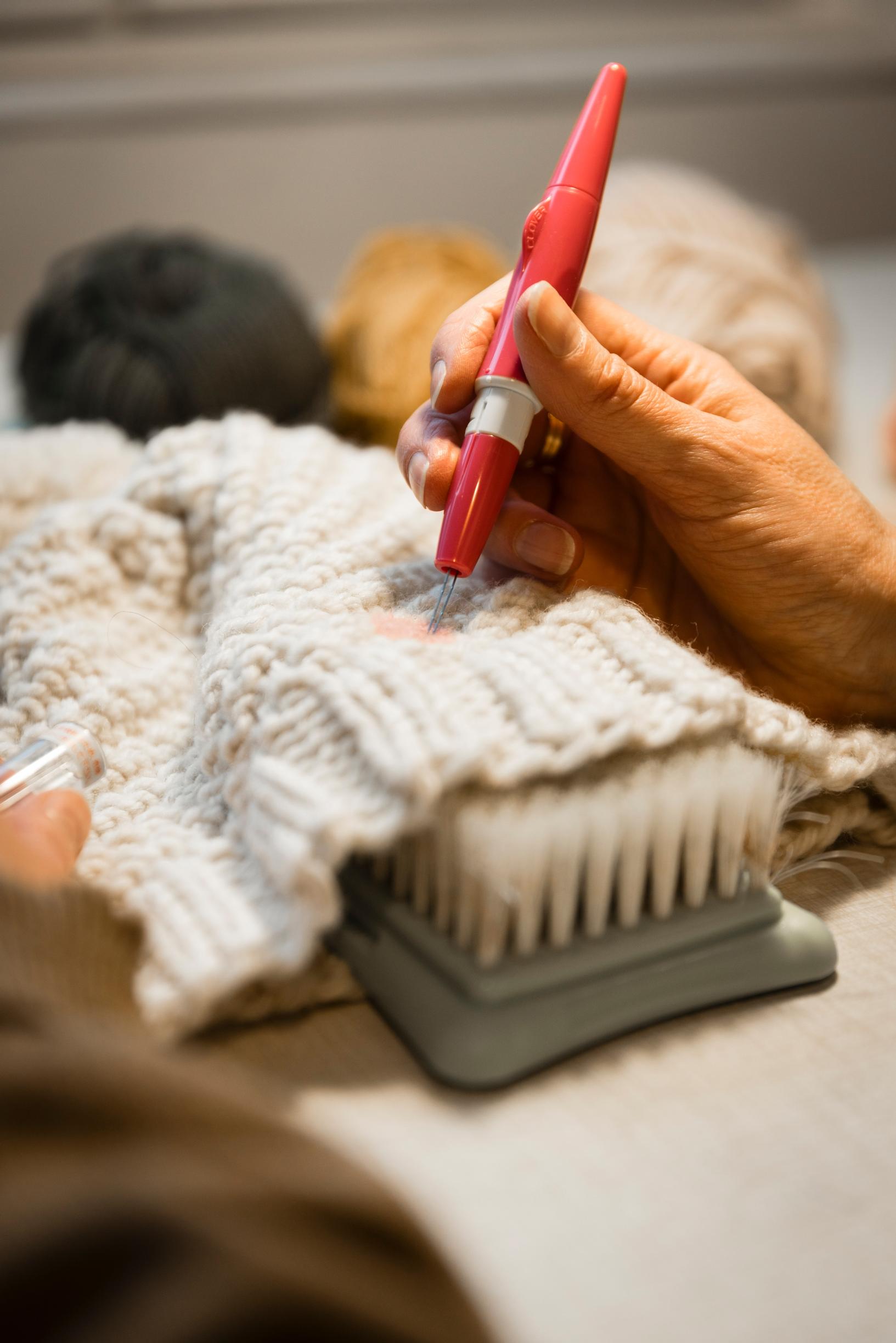 Minttu Wikberg makes a patch on a knitted hat by needle-felting.