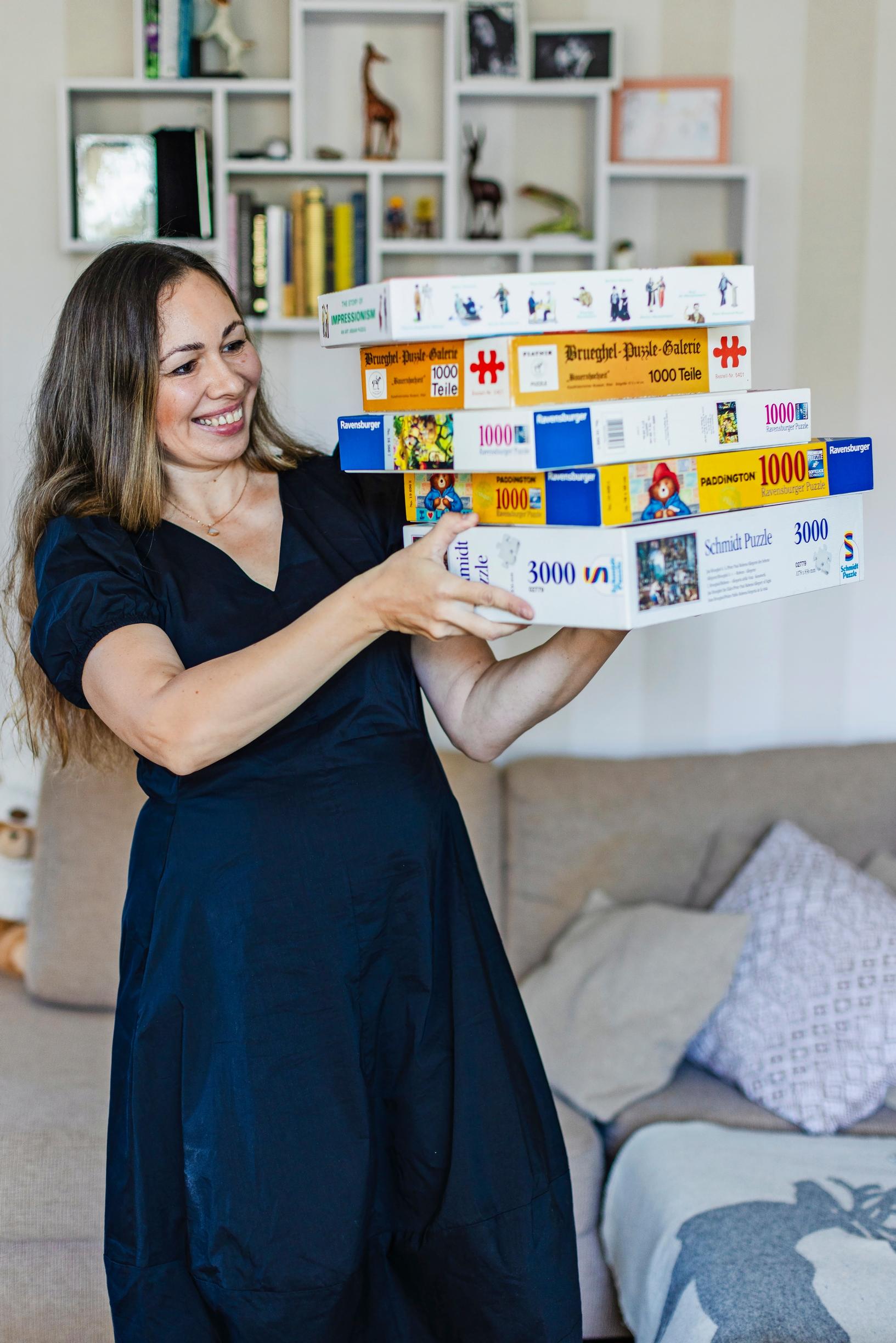 Photo of a jigsaw puzzle enthusiast with a stack of puzzles.