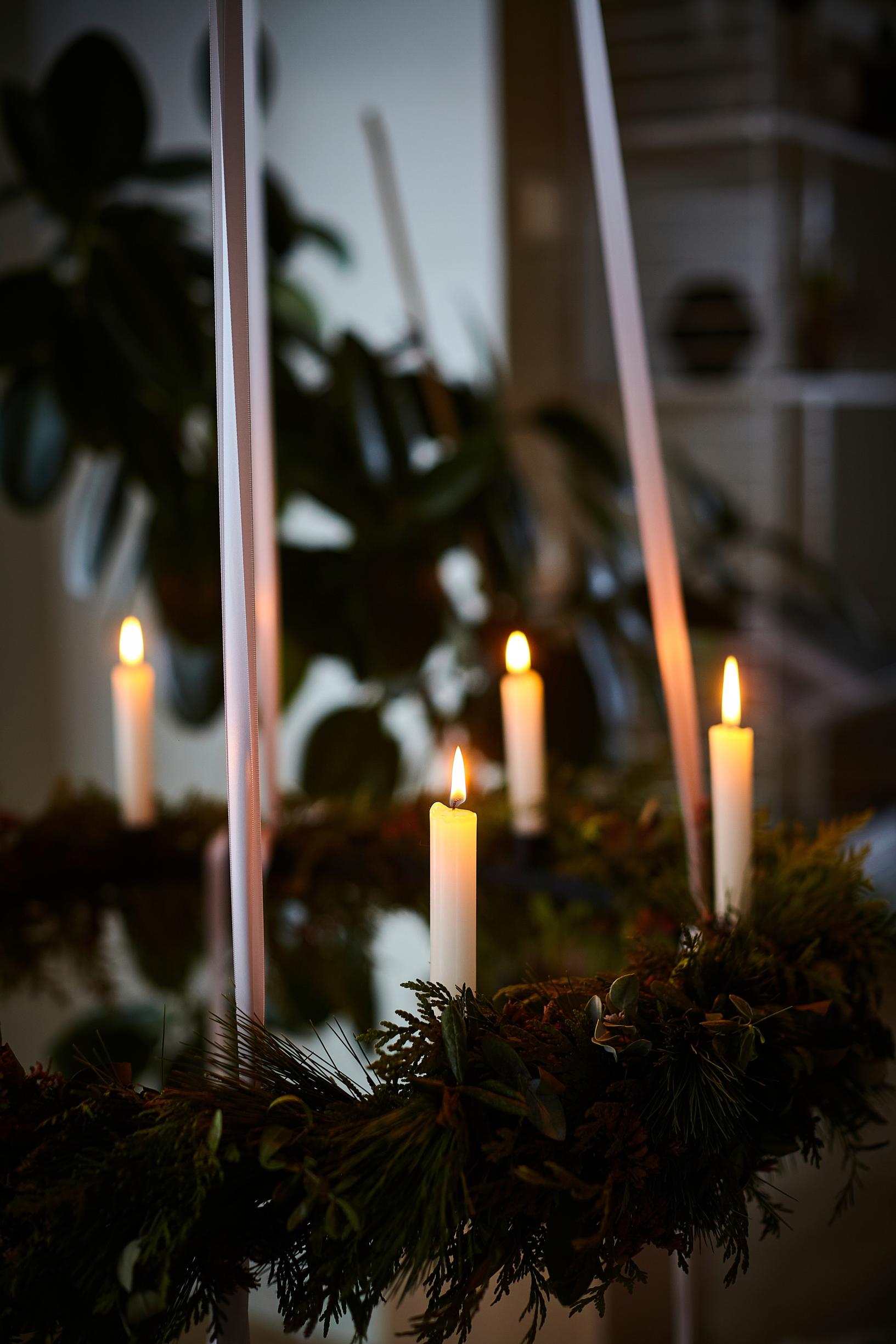 White candles burning inside a wreath of evergreen branches