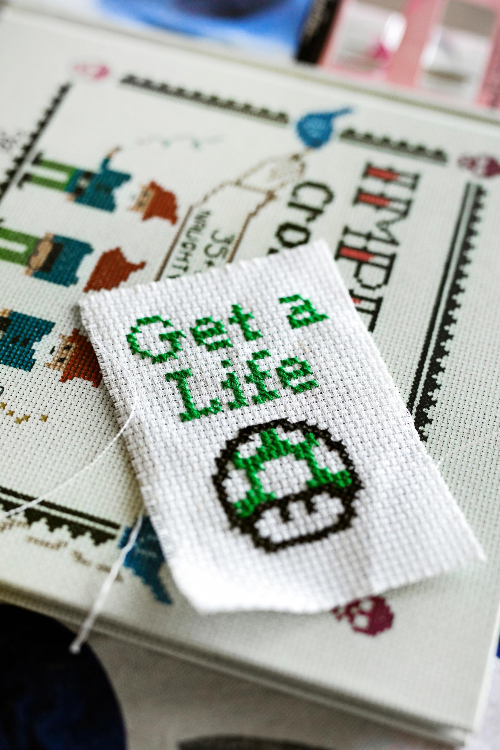 A cross-stitch work featuring the familiar mushroom from the Super Mario game and the text ‘Get a Life’