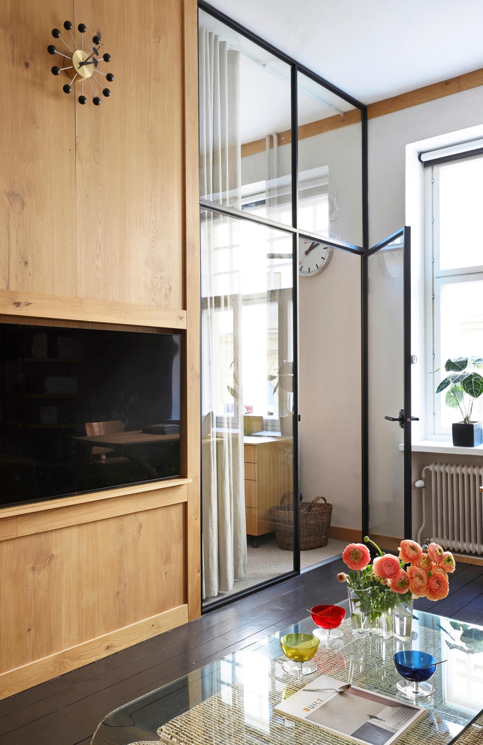 The television embedded in the wall panel is along the walkway. A coffee table sits in front of the television.