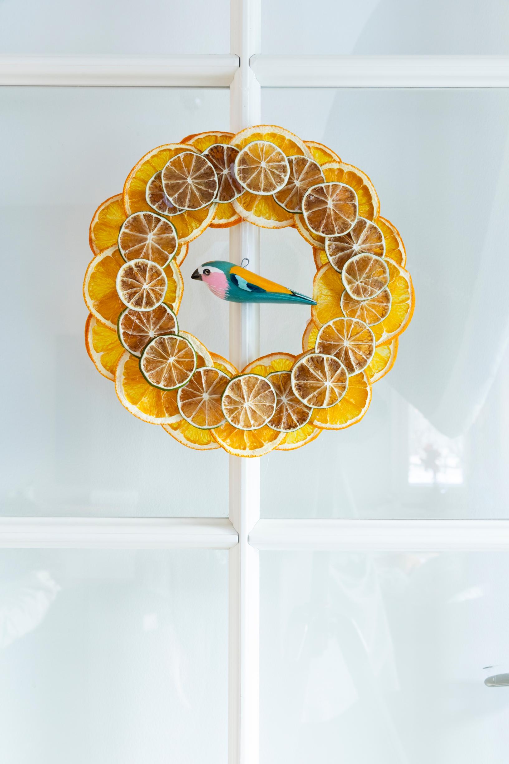A wreath made of dried orange slices, with a parrot in the center.