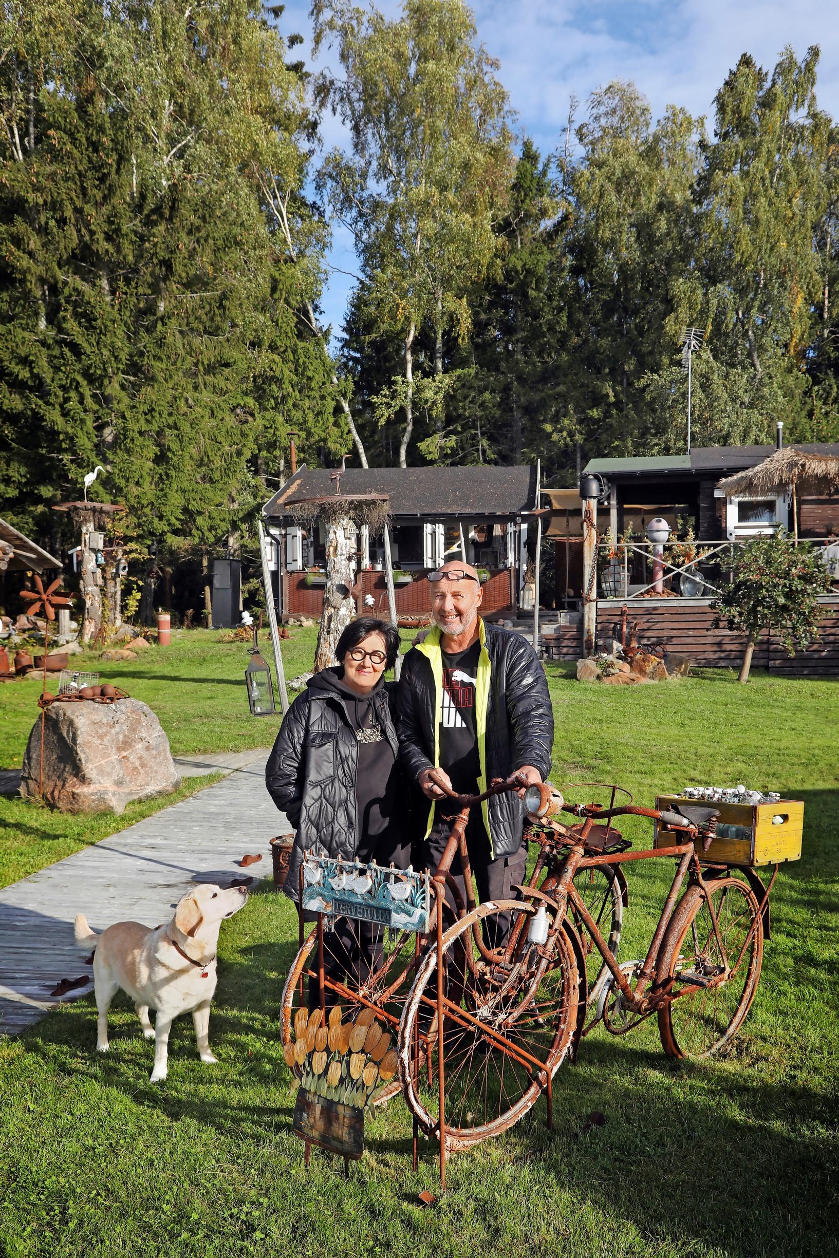 Sanna and Markku Parkkari next to rusty bicycles with their dog.