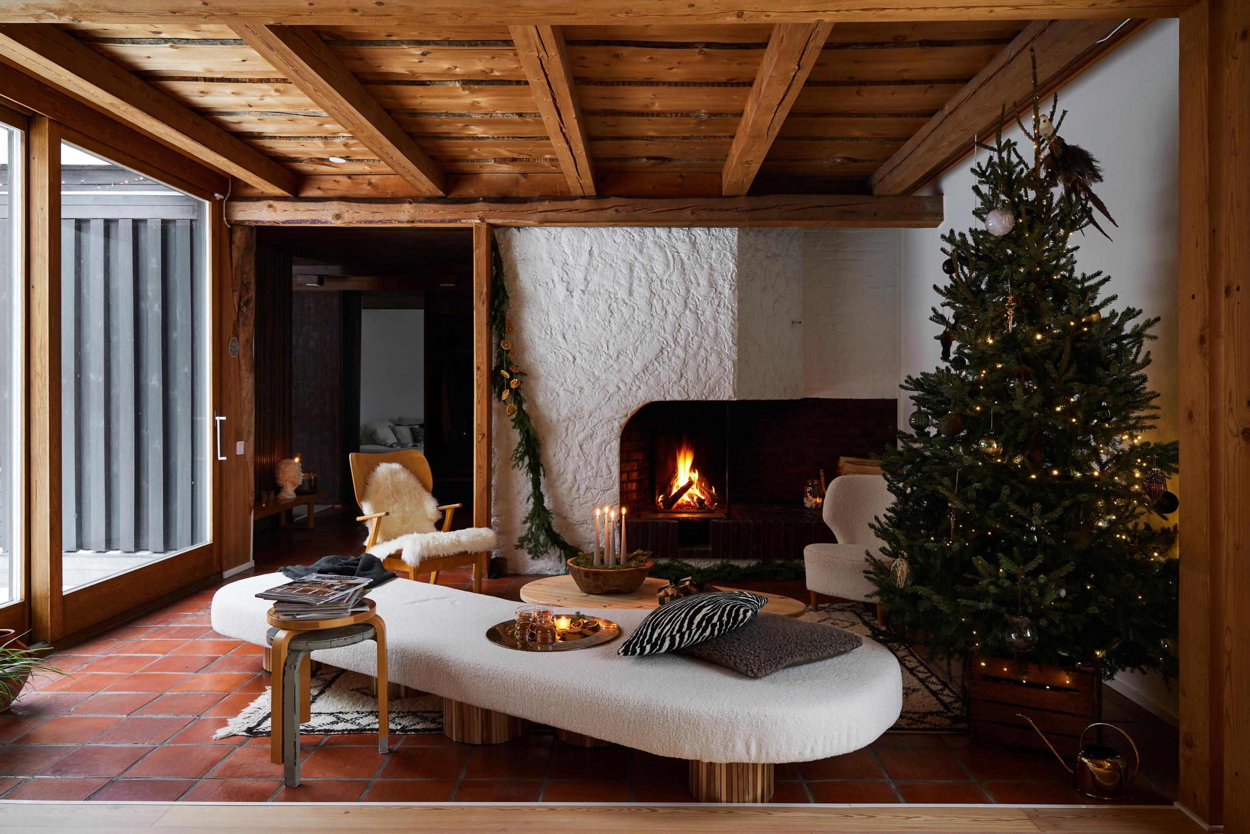 In the living room, a daybed and open fireplace, plus the original aged-pine ceiling and terracotta tile floor.