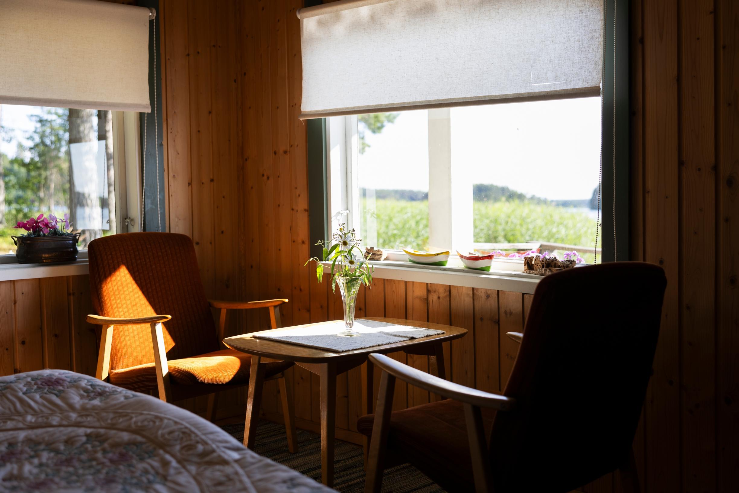 Old armchairs around a small table, two windows with a view of reeds and the lake