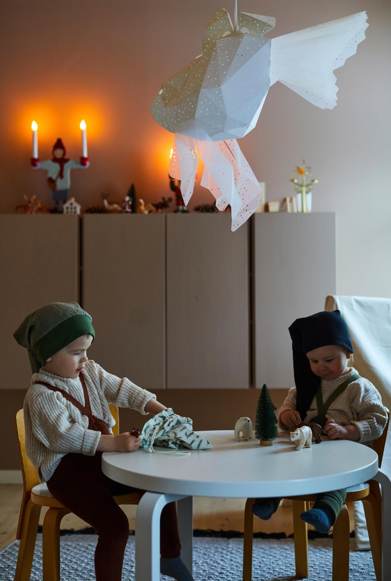 Jens and Jose sit at a table playing while wearing elf hats, with candles on top of the cabinet
