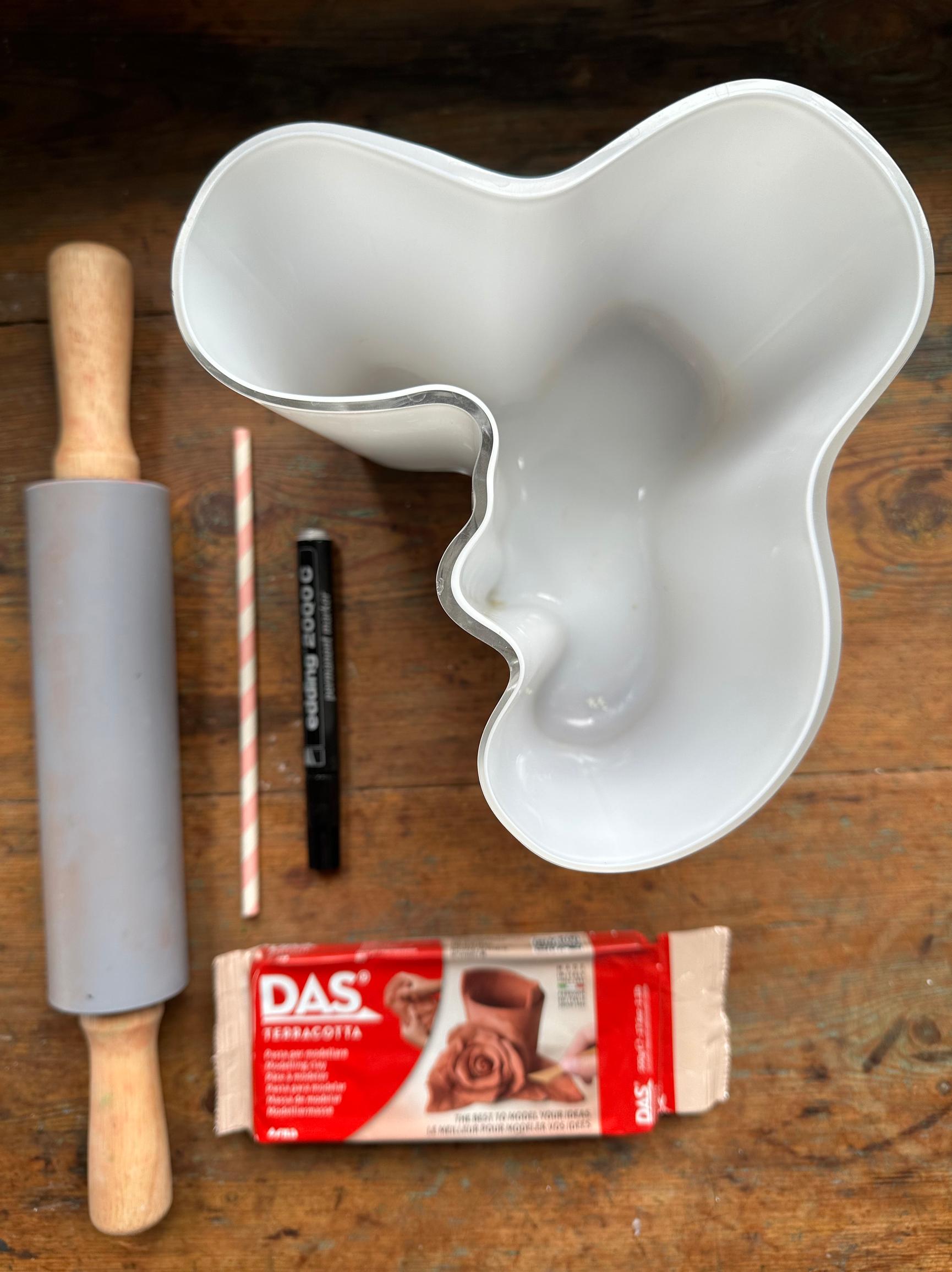 On the table: air-dry clay, rolling pin, straw, marker, and vase.