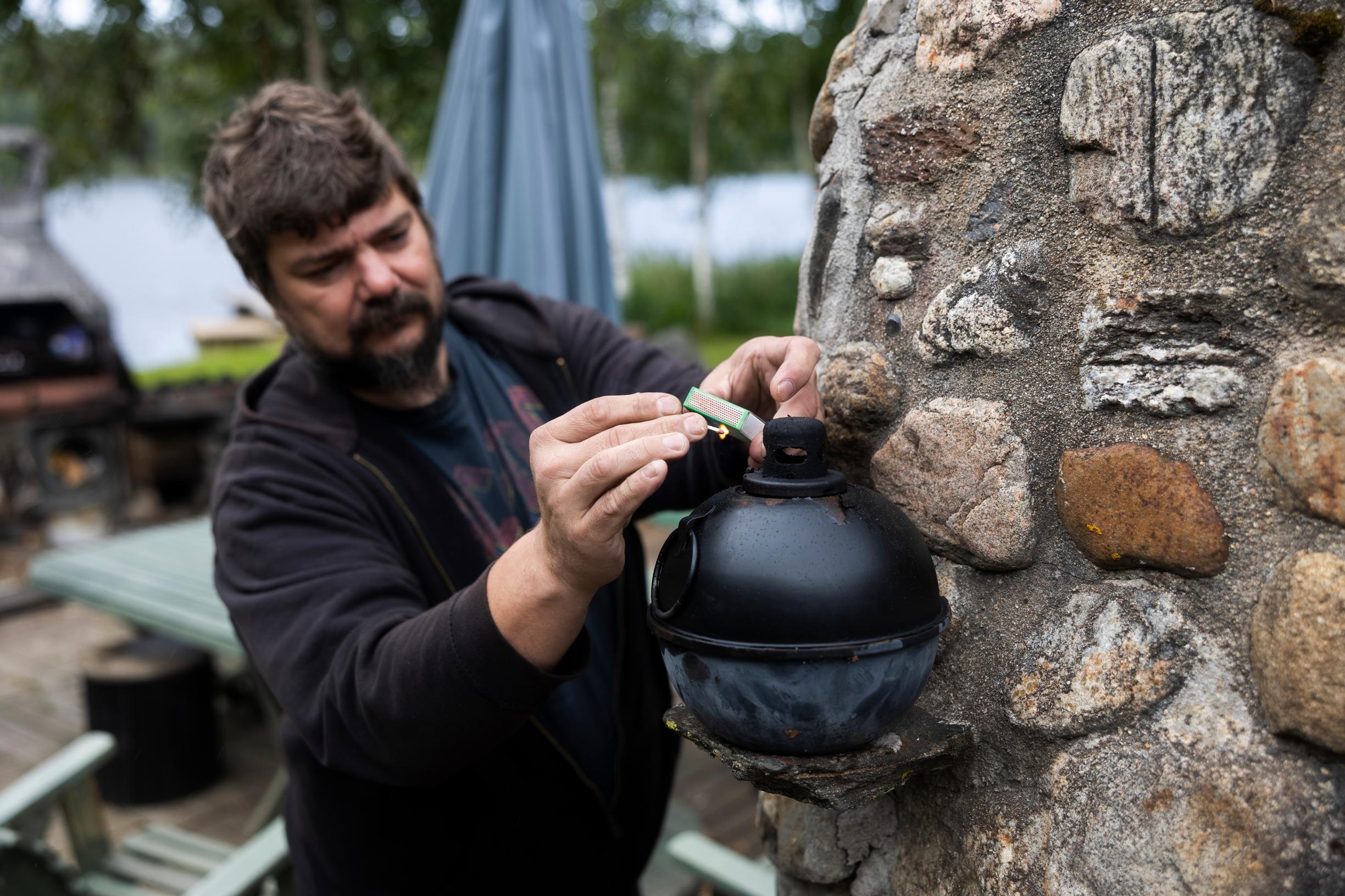 A man tinkering in the garden by the stone sauna
