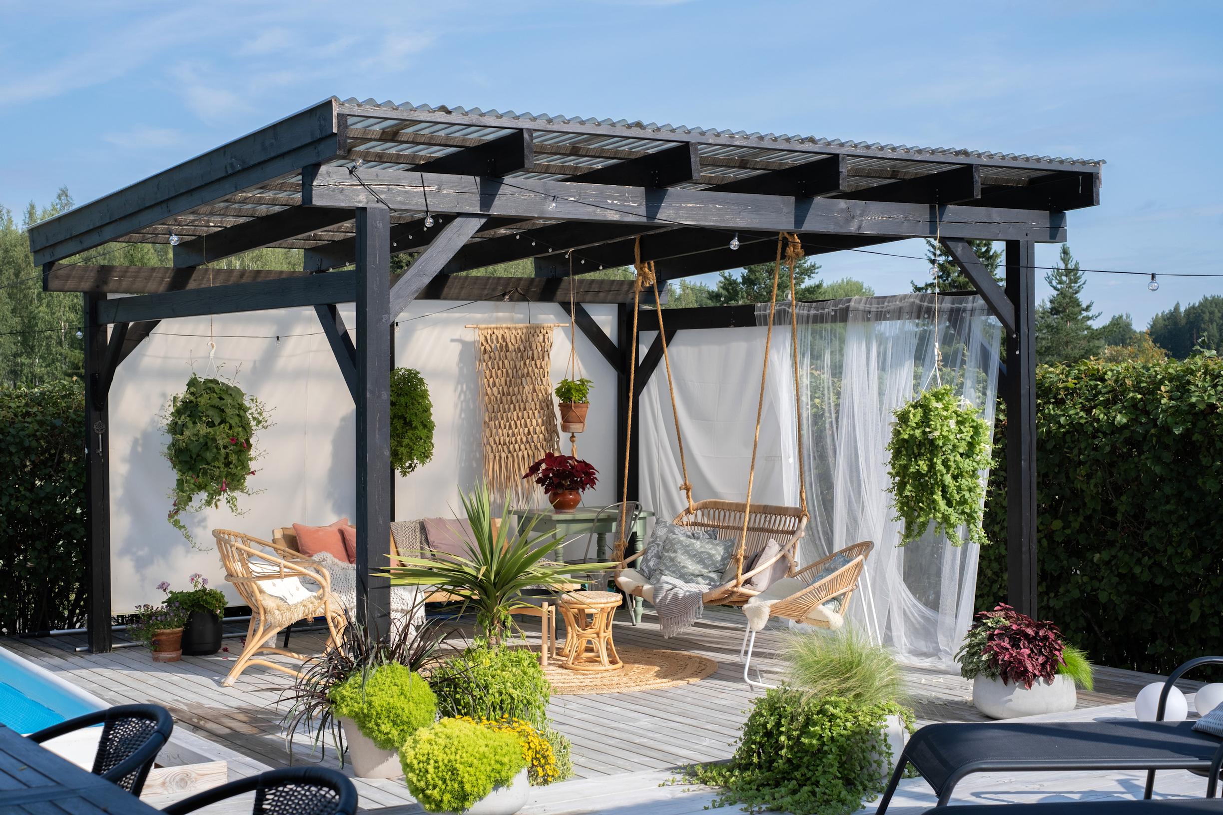 A translucent roof covers the pergola. A sunshade is stretched across the back wall.