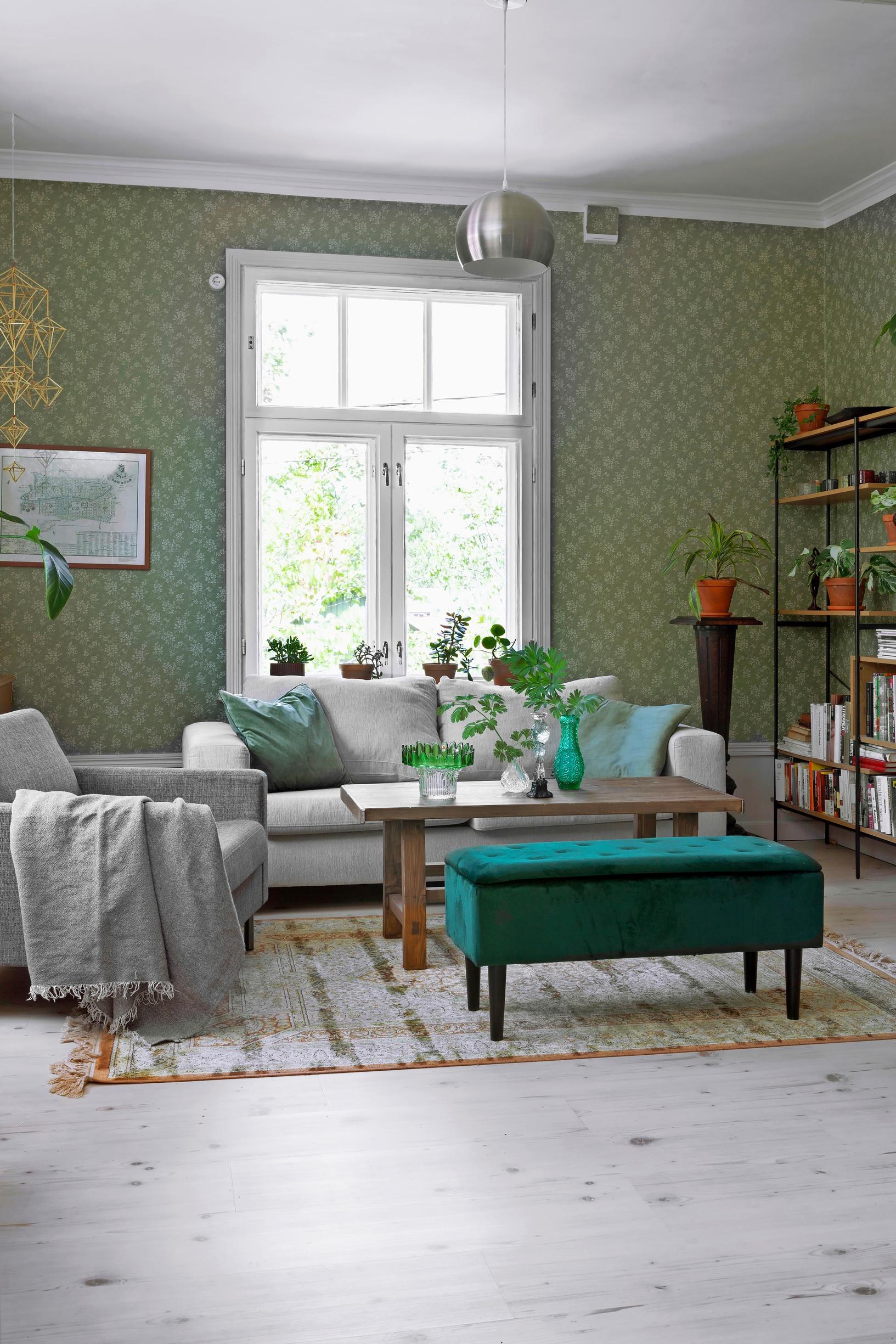 A photo of the living room with secondhand light-colored sofas and a green velvet ottoman.