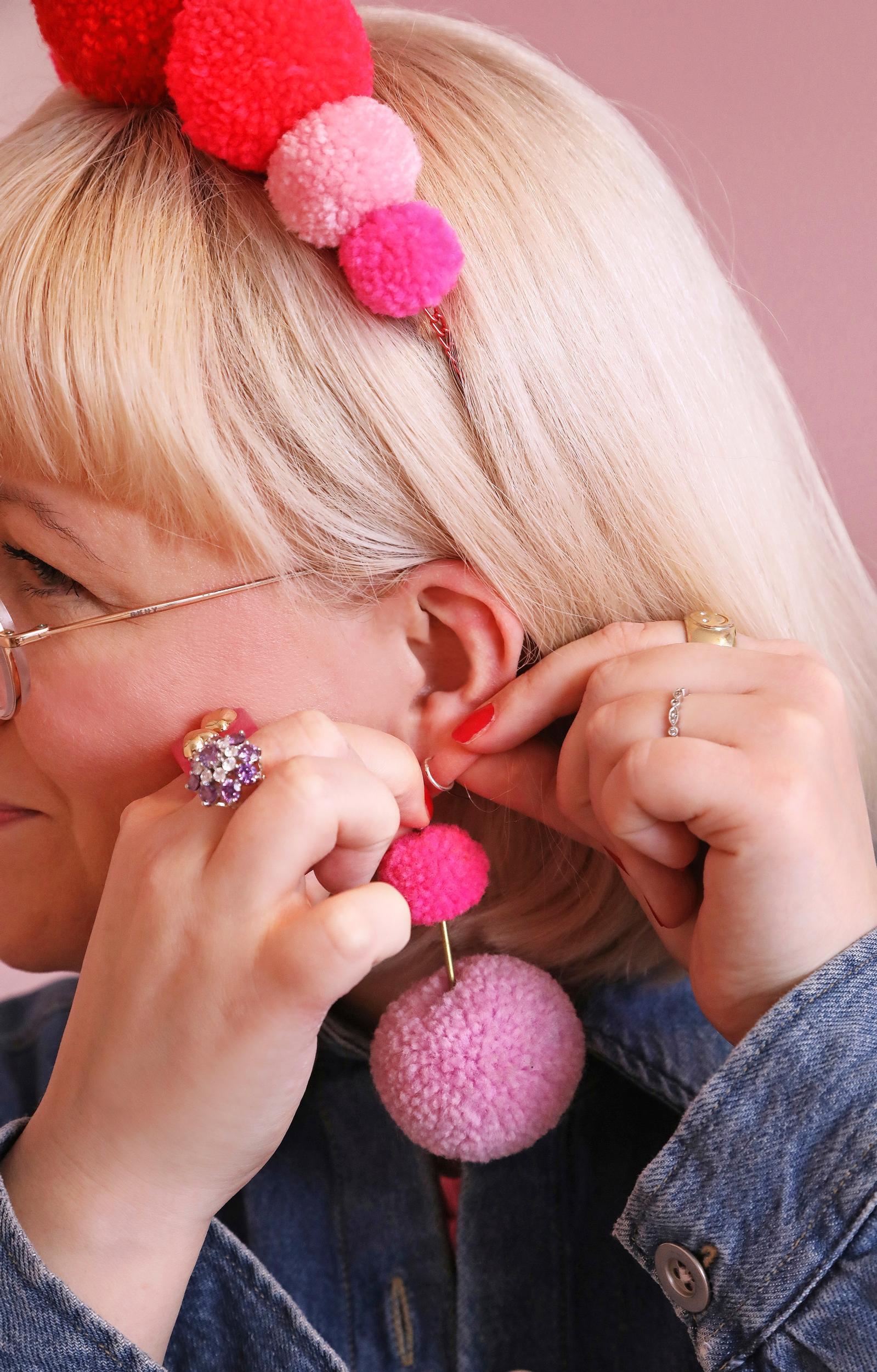 Mari wearing pink pom-pom earrings.
