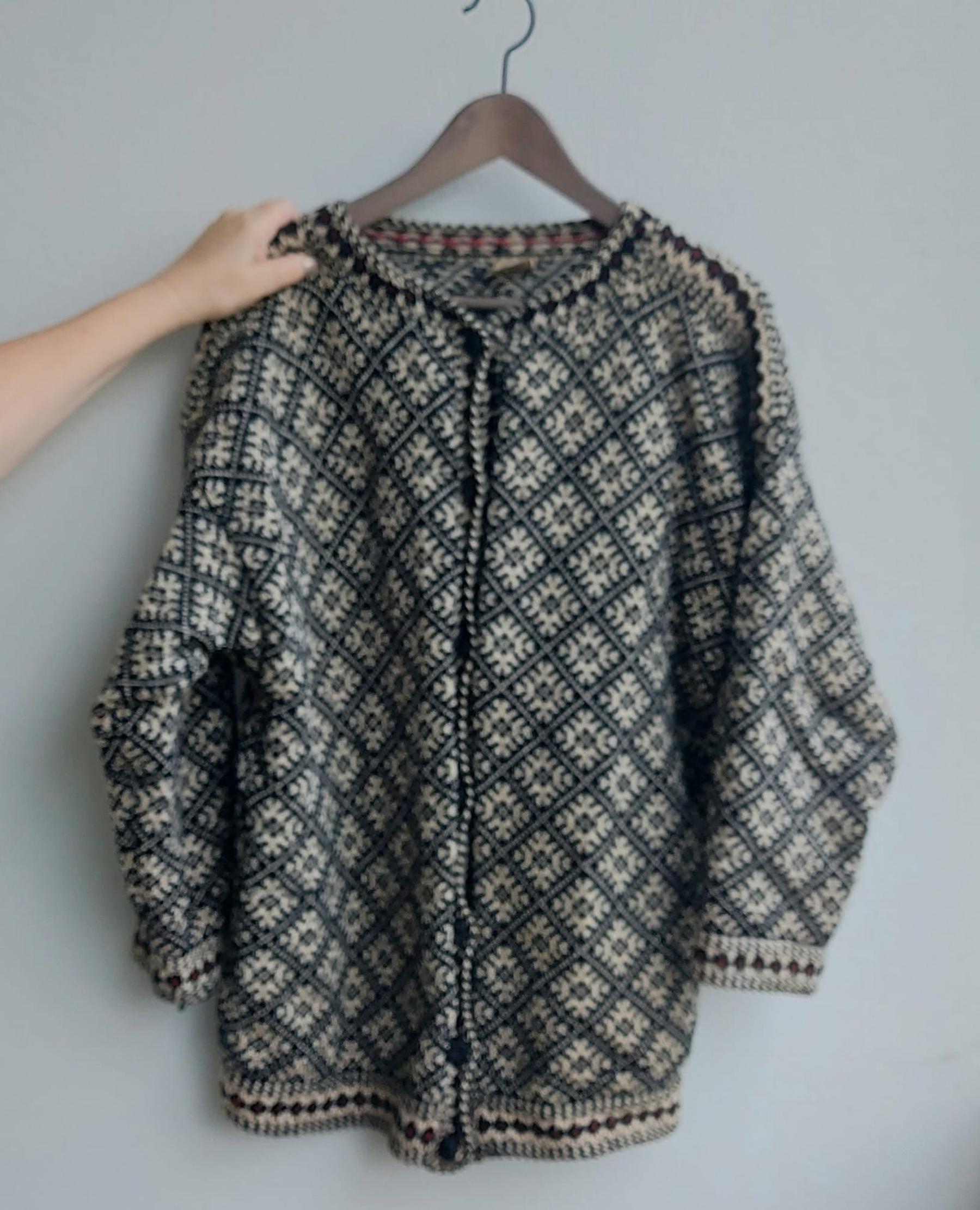 A colorwork knit cardigan on a hanger