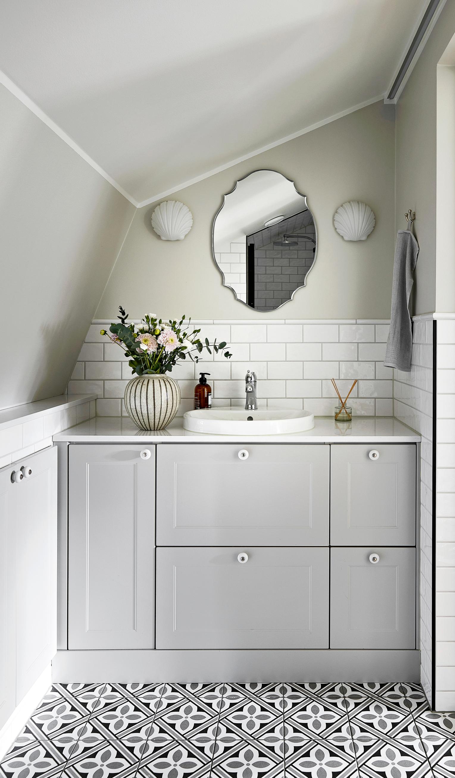 Soft light tones, patterned tile floor, and an oval mirror in the bathroom