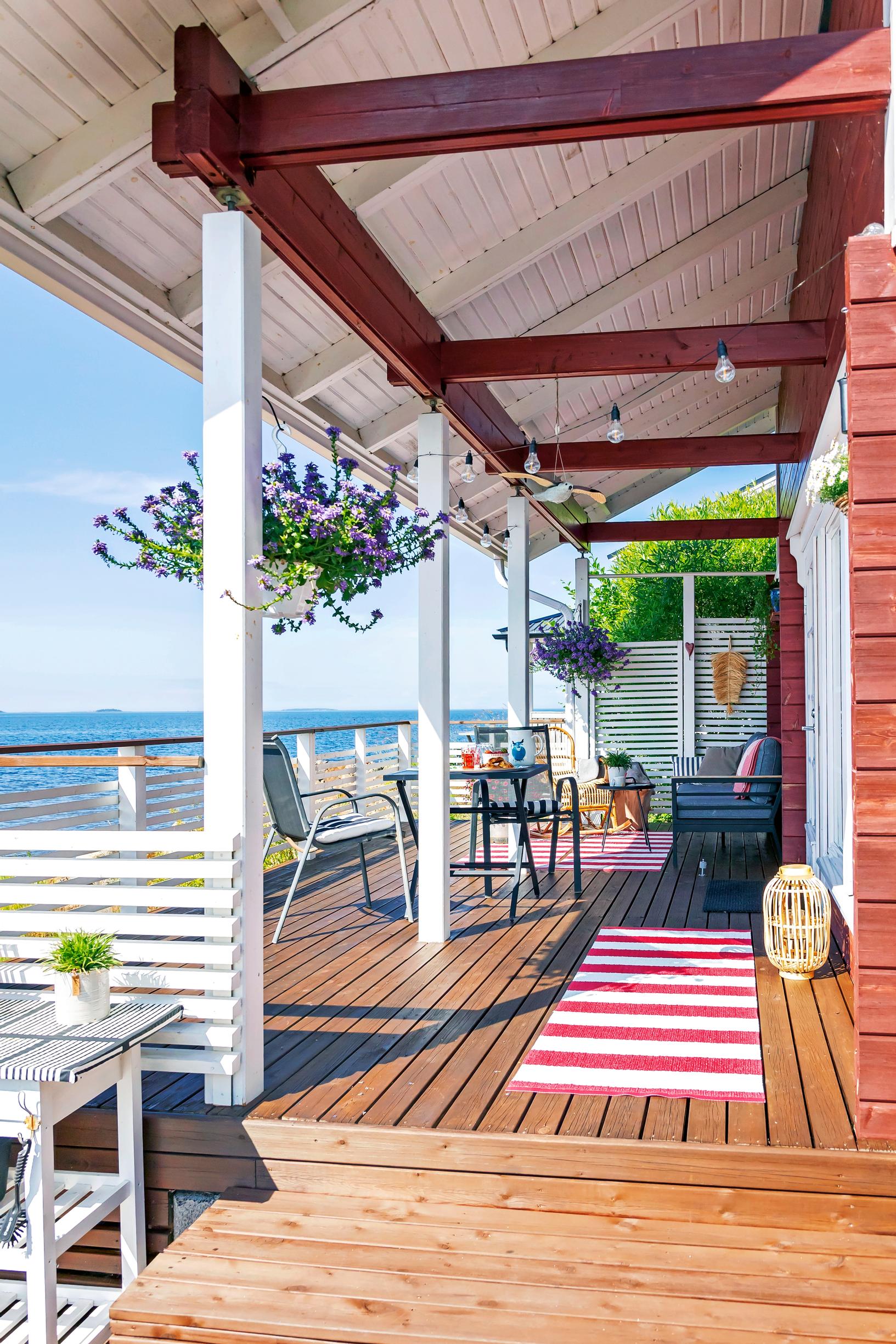 a long covered terrace, a rug, furniture, and a sea view