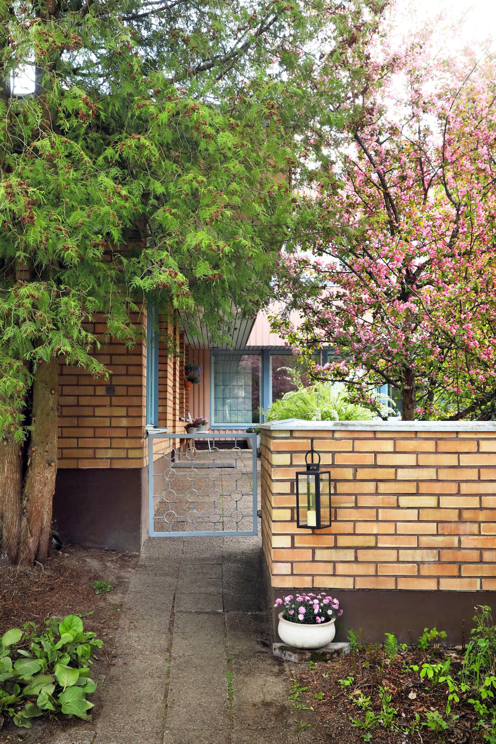 Photo of the garden of the 1970s detached house with a brick wall and gate.