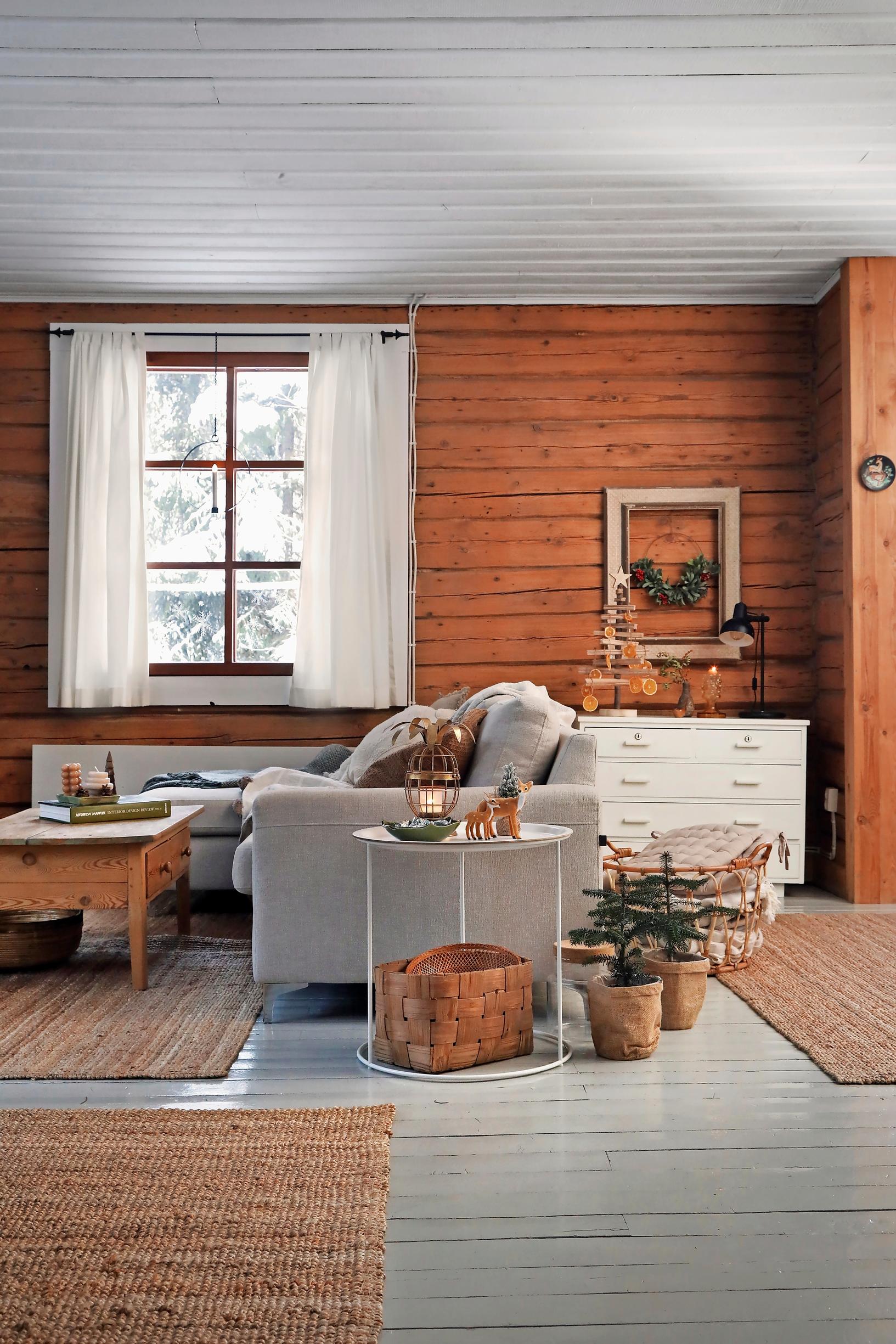 in the cabin’s living room, a light sofa, wooden coffee table, and brown rugs