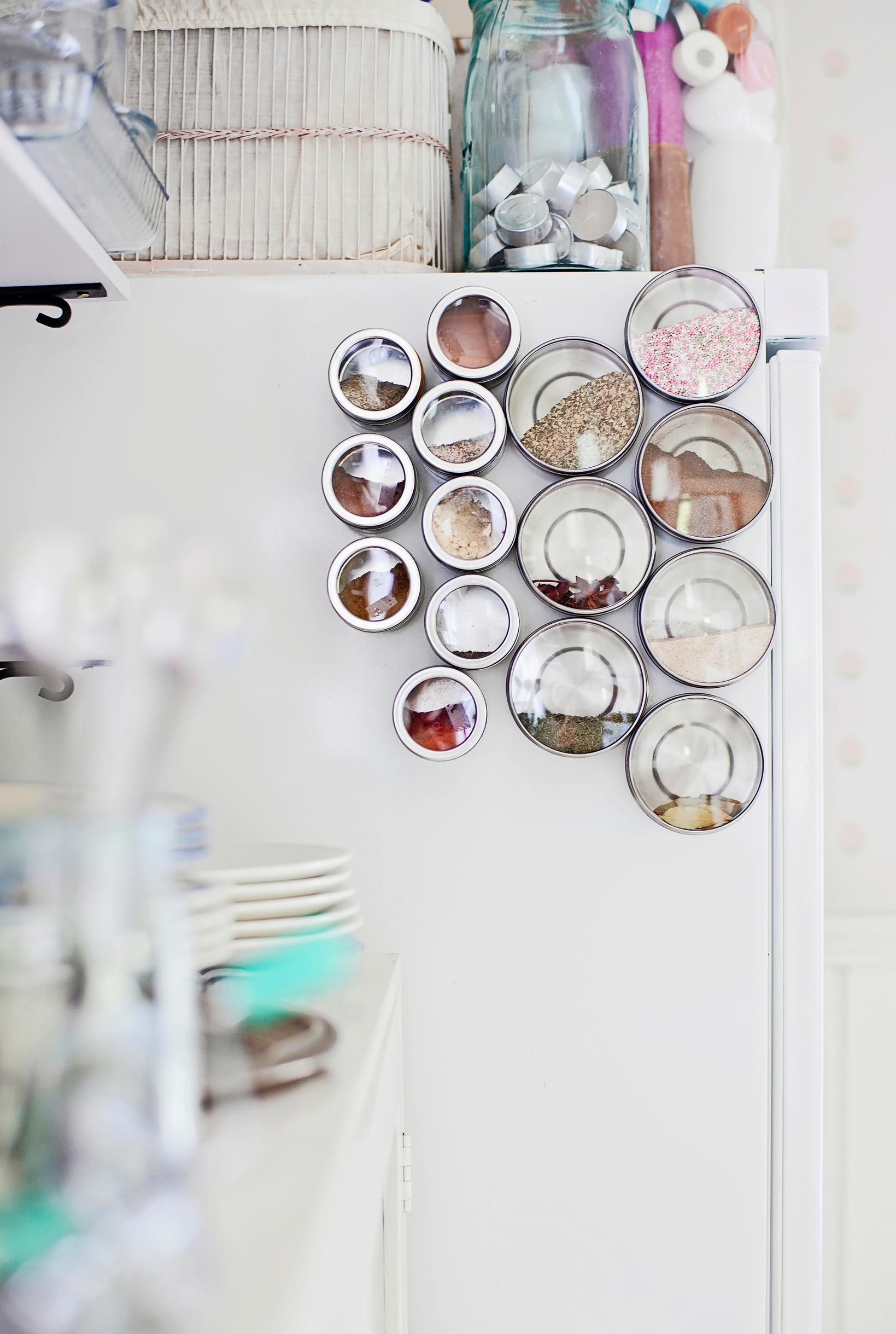 Spice jars with magnets on their bottoms on a refrigerator door